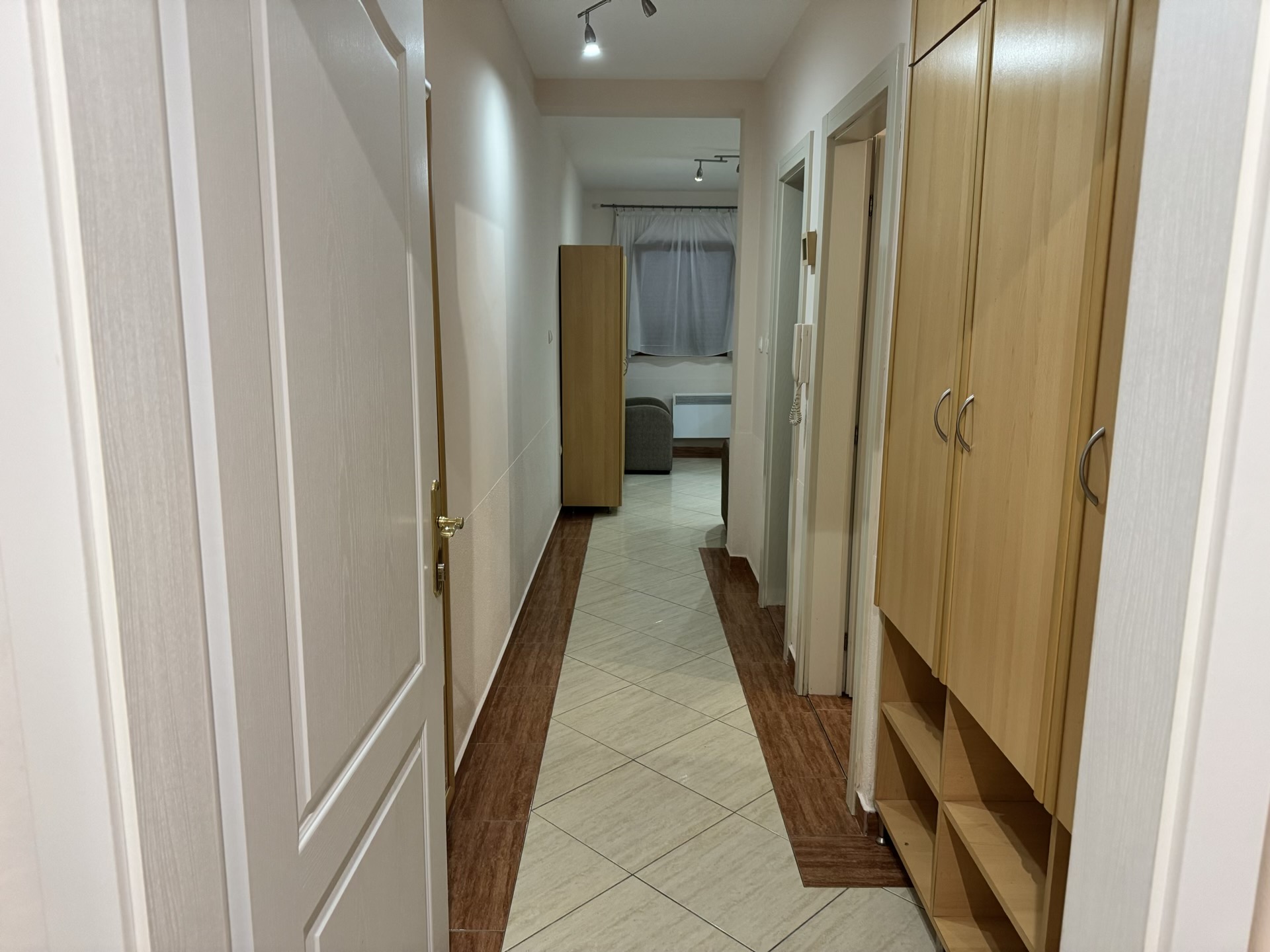 Heller Flur in einer Wohnung in Budva, Montenegro: Einbauschrank, Fliesenboden und Innentüren.