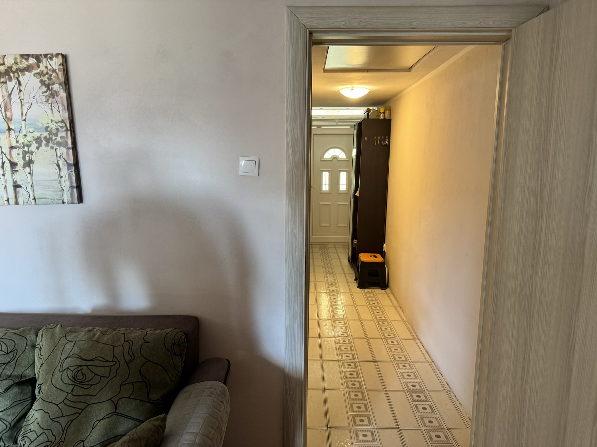 Blick vom Wohnzimmer in den Flur der Wohnung in Bečići, Montenegro: helle Ausstattung, Fliesenboden und Eingangstür.
