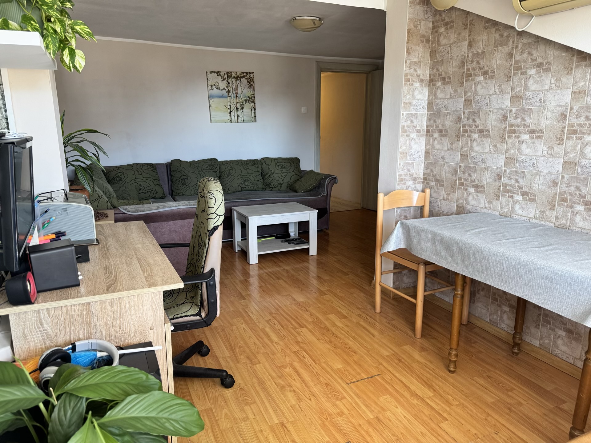 Wohnzimmer in einer Wohnung in Bečići, Montenegro: Sofa, Essbereich, Schreibtisch und Wandverkleidung mit dekorativen Fliesen.