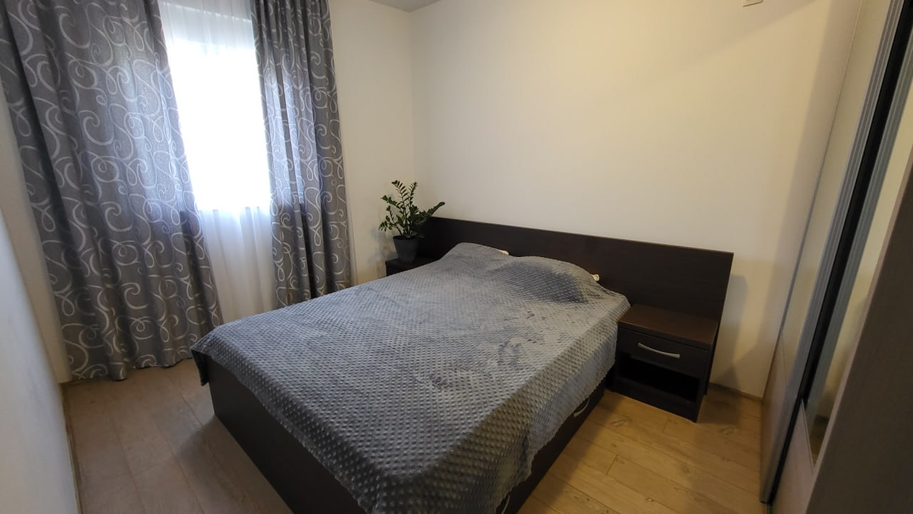 Gemütliches Schlafzimmer in einer Wohnung in Bečići, Montenegro: Doppelbett, dunkle Möbel, helle Wände und gemusterte Vorhänge.