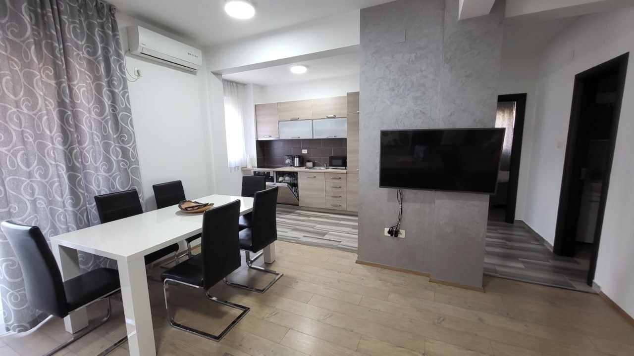 Wohnzimmer mit Essbereich und moderner Küche in einer Wohnung in Bečići, Montenegro: helles Interieur, TV und Möbel.
