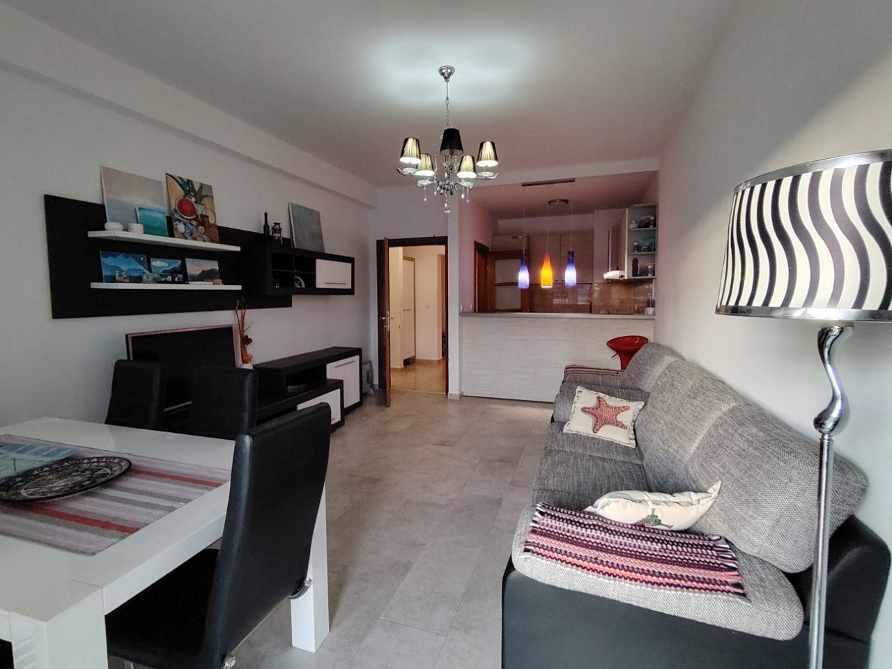 Salon avec coin repas et cuisine dans un appartement, Seoc, Monténégro : mobilier moderne, canapé gris et décoration élégante.