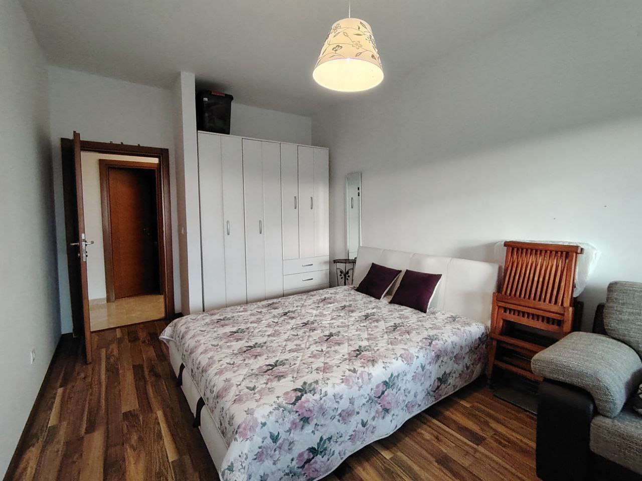 Chambre dans un appartement à Sutomore, Monténégro : lit double, armoire blanche, parquet en bois et intérieur chaleureux.