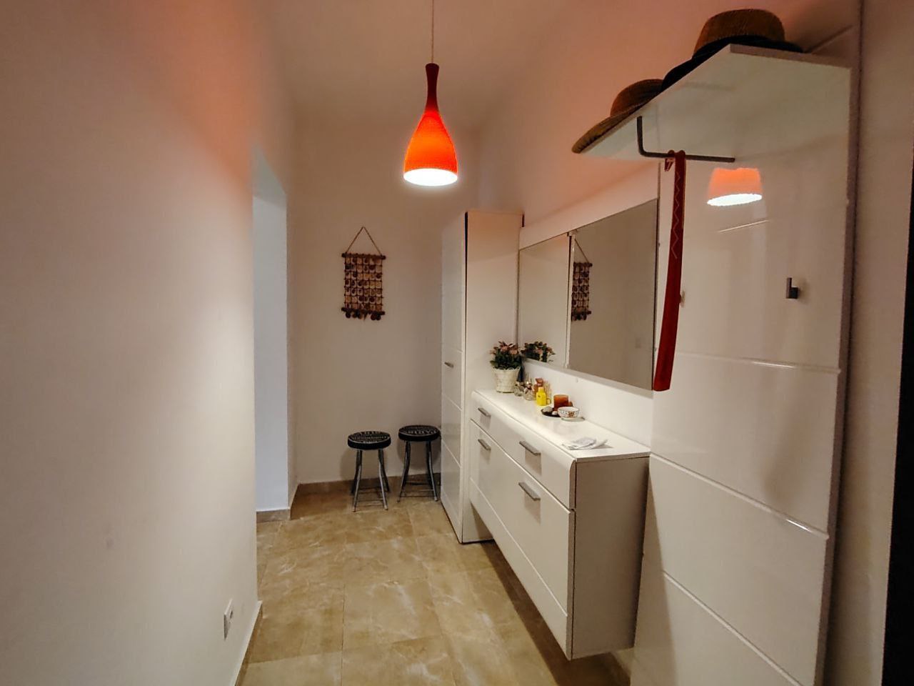 Hall d’entrée lumineux avec mobilier blanc et miroir dans un appartement, Seoc, Monténégro. Intérieur moderne avec un éclairage vif.
