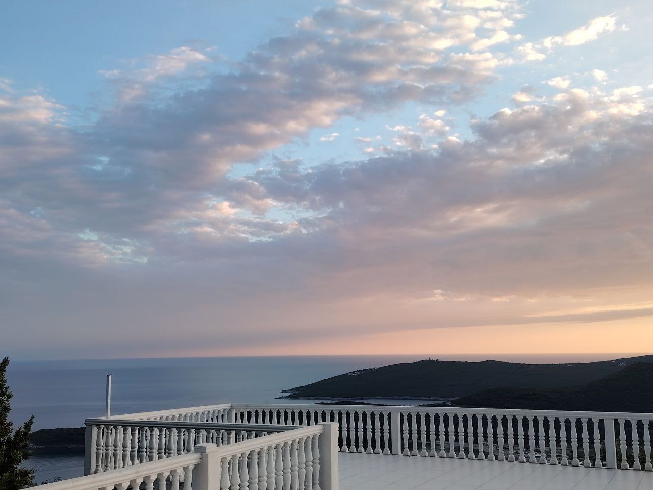 Vue panoramique sur la mer et les montagnes depuis une spacieuse terrasse avec balustrade blanche dans un appartement, Seoce, Monténégro.