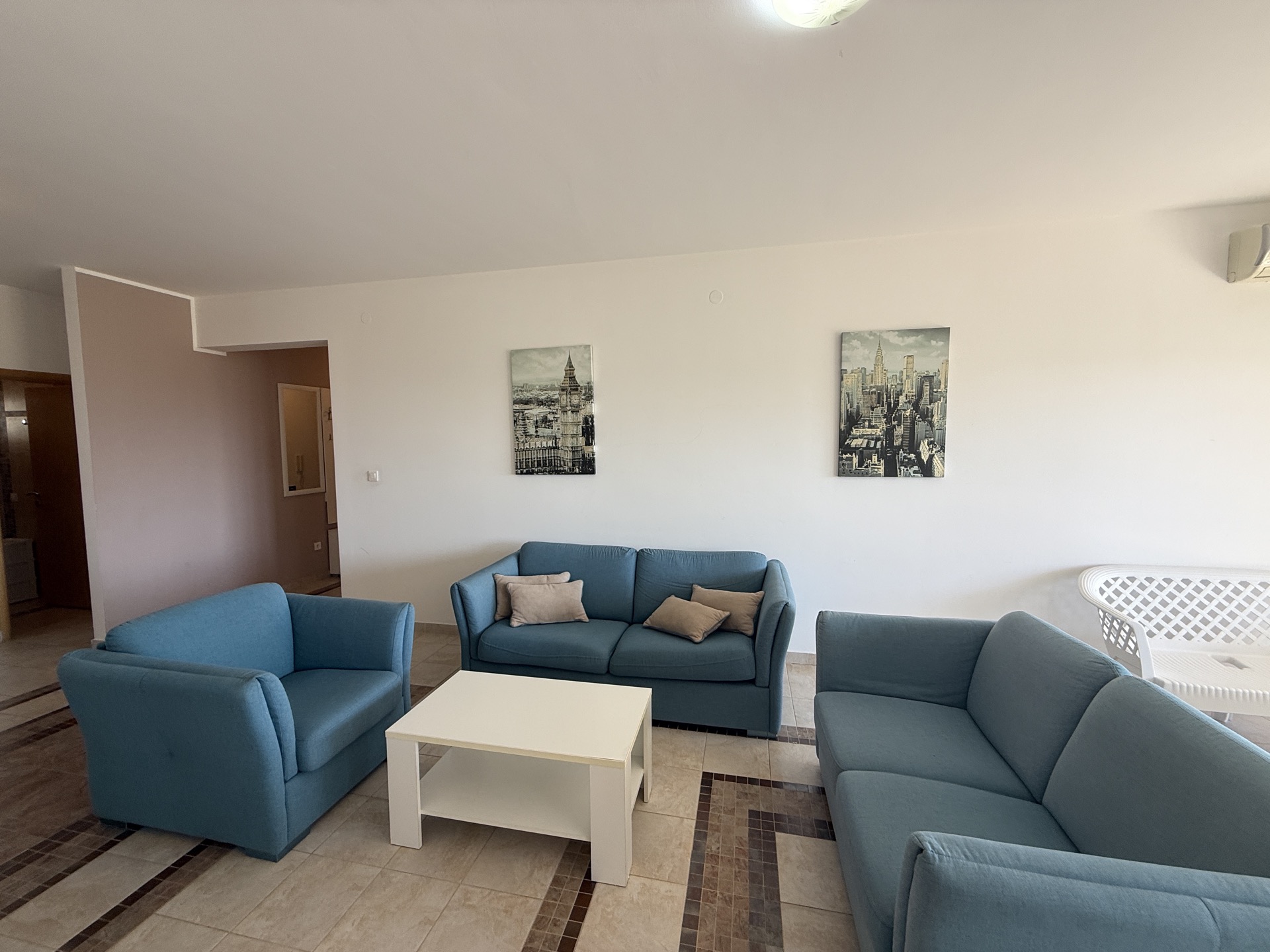Jasny salon z niebieskimi sofami i stolikiem kawowym w mieszkaniu na sprzedaż, Budva, Czarnogóra.