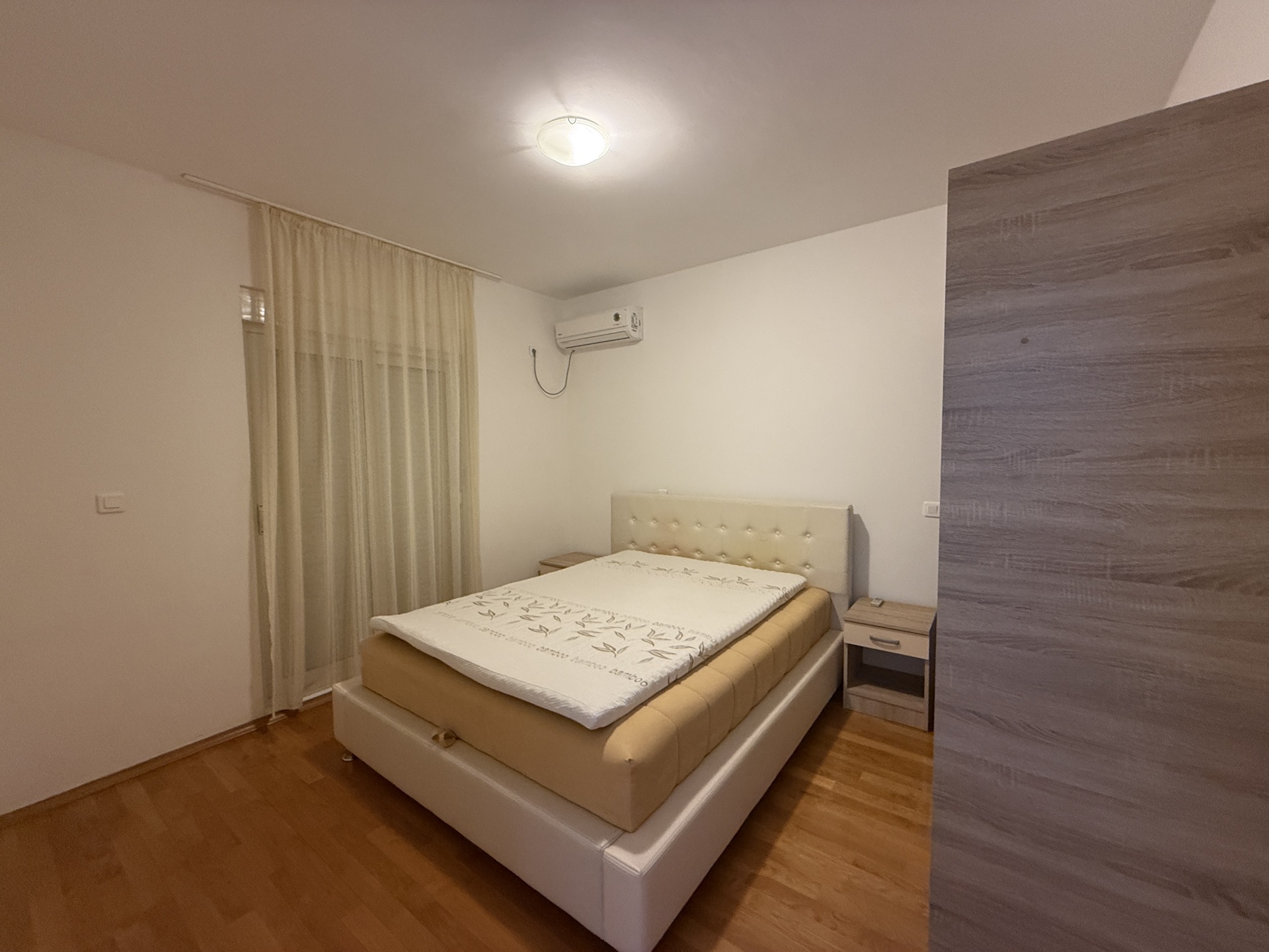 Przytulna sypialnia z łóżkiem dwuosobowym i klimatyzacją w mieszkaniu na sprzedaż, Budva, Czarnogóra.