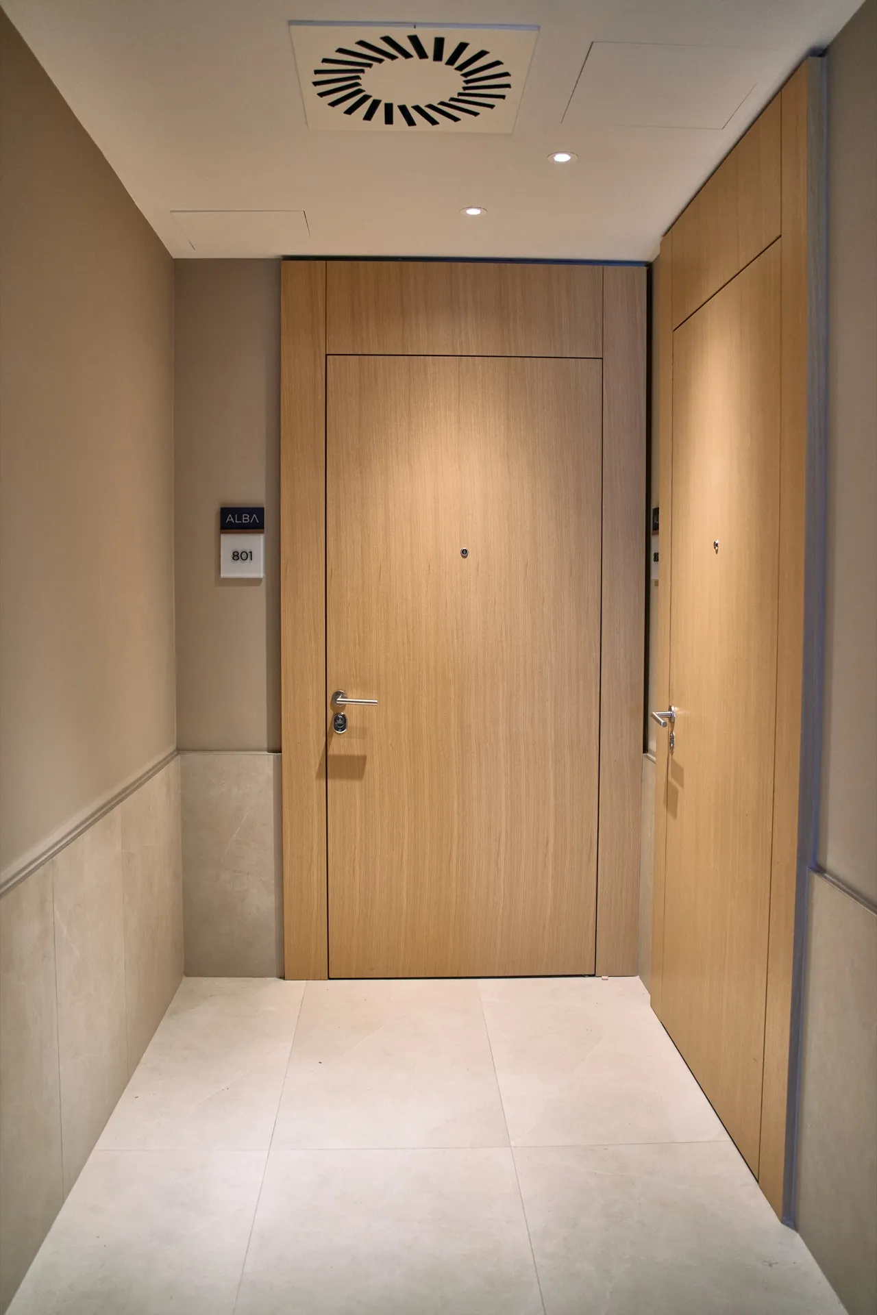 Wohnungshalle mit einer Holztür mit der Nummer 801 und hellen Fliesenboden.