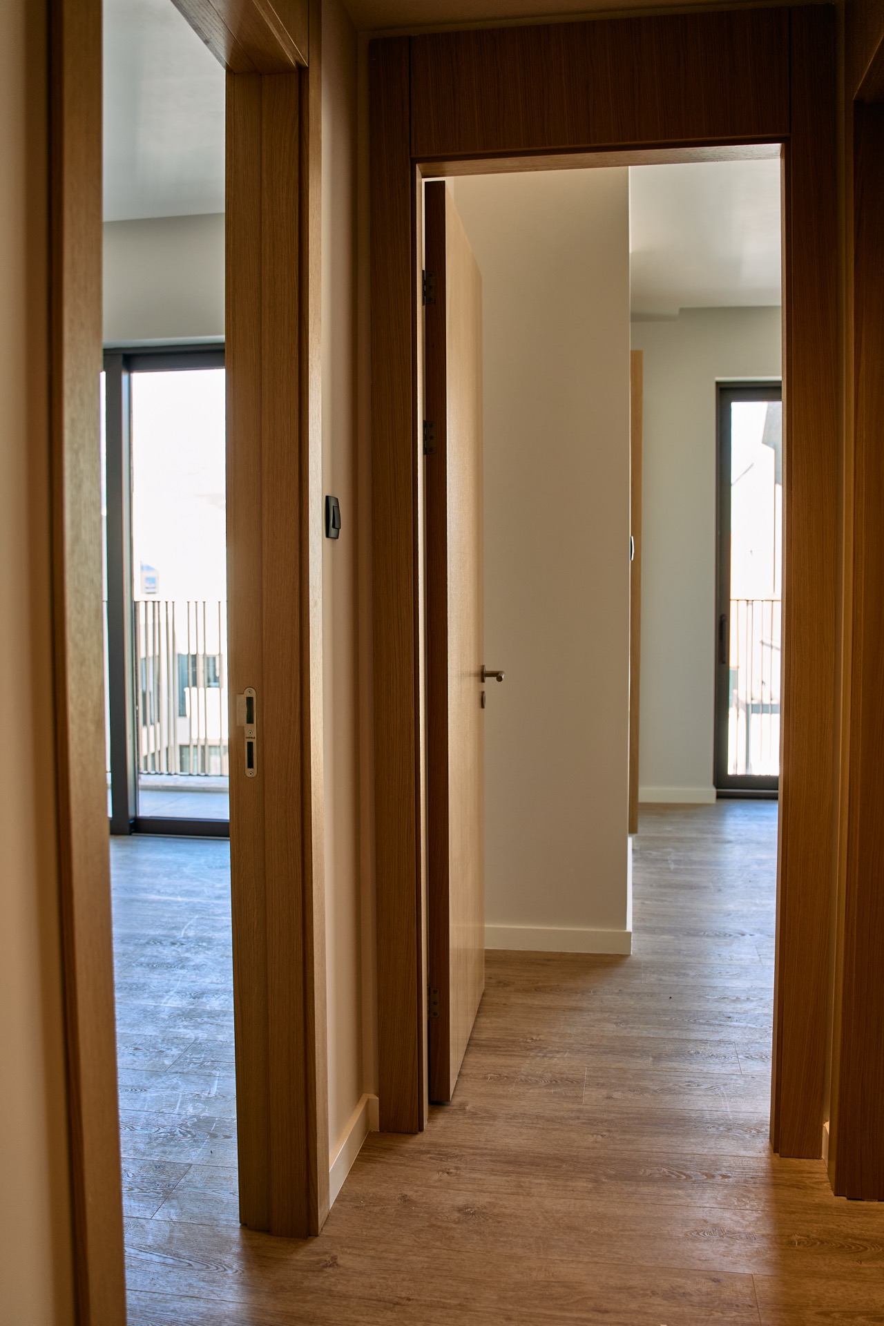 Modernes Interieur einer Wohnung in Porto Montenegro, Tivat: heller Flur mit Holztüren und Zugang zum Balkon.