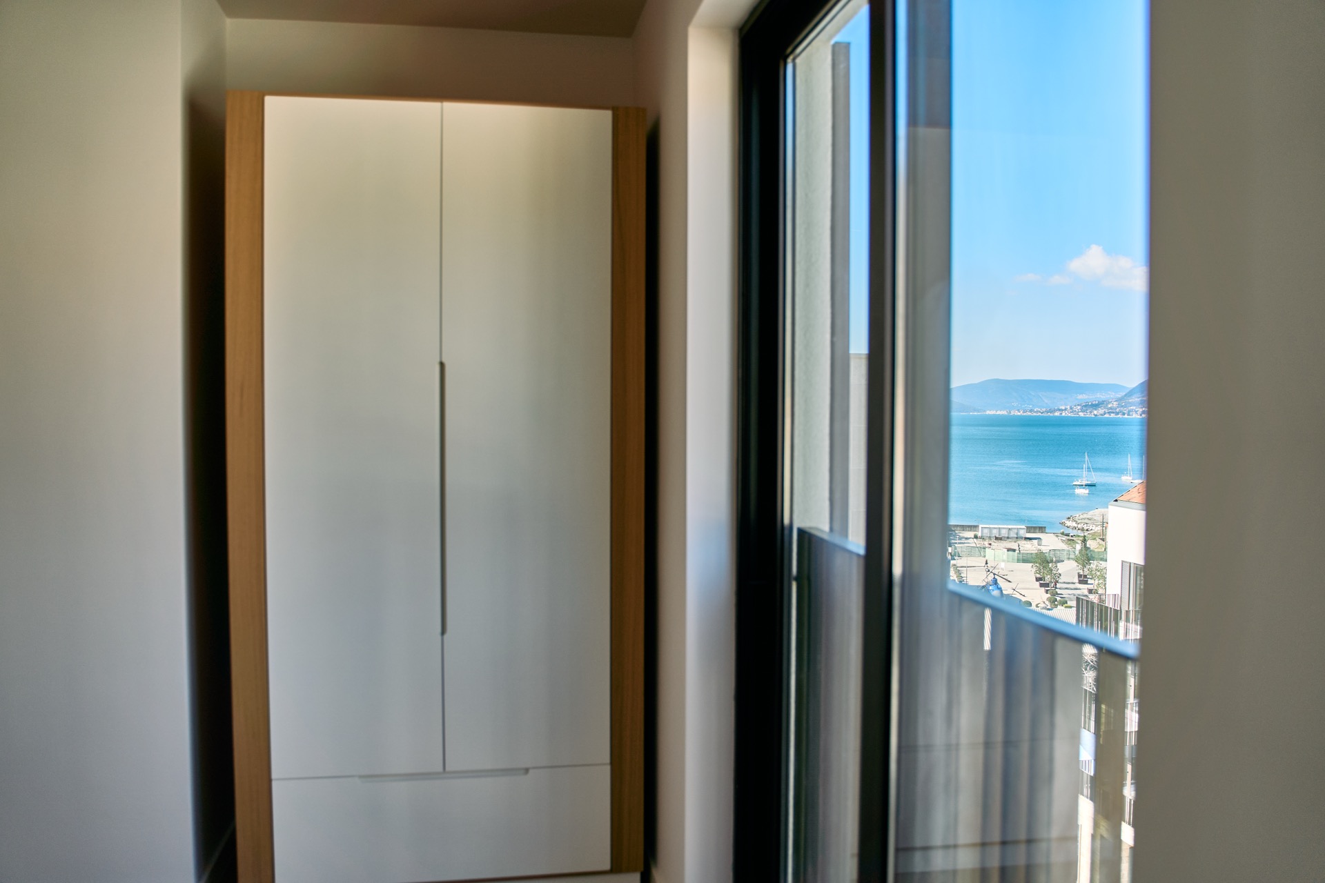 Schlafzimmer in einer Wohnung in Porto Montenegro, Tivat, Montenegro: Einbauschrank und Panoramablick auf das Meer und den Yachthafen.
