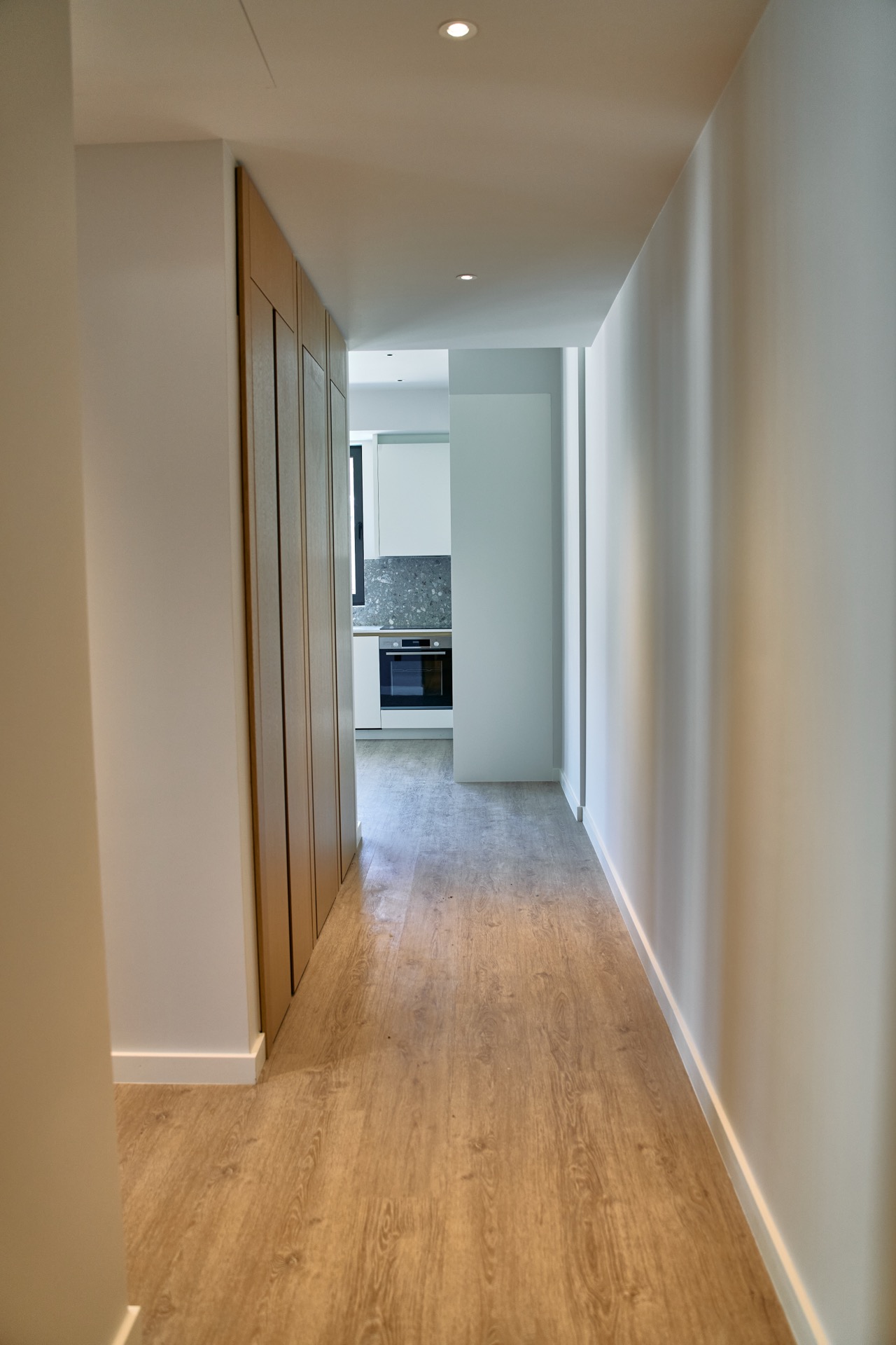 Flur mit Holzschränken und Blick auf die moderne Küche in einer Wohnung im ЖК Porto Montenegro, Tivat, Montenegro.