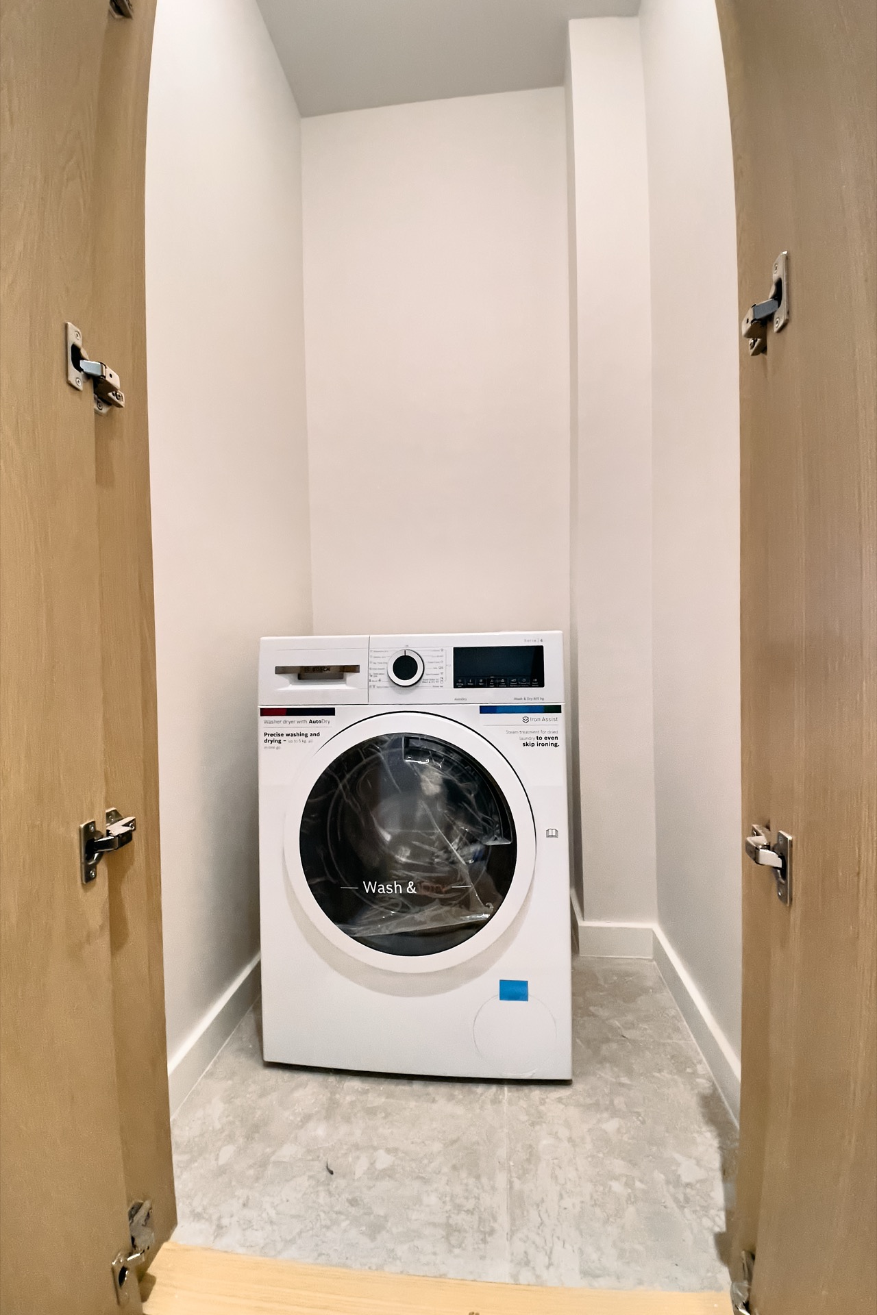 Bosch-Waschmaschine in einer Nische mit Holztüren in einer Wohnung, Porto Montenegro, Tivat, Montenegro.