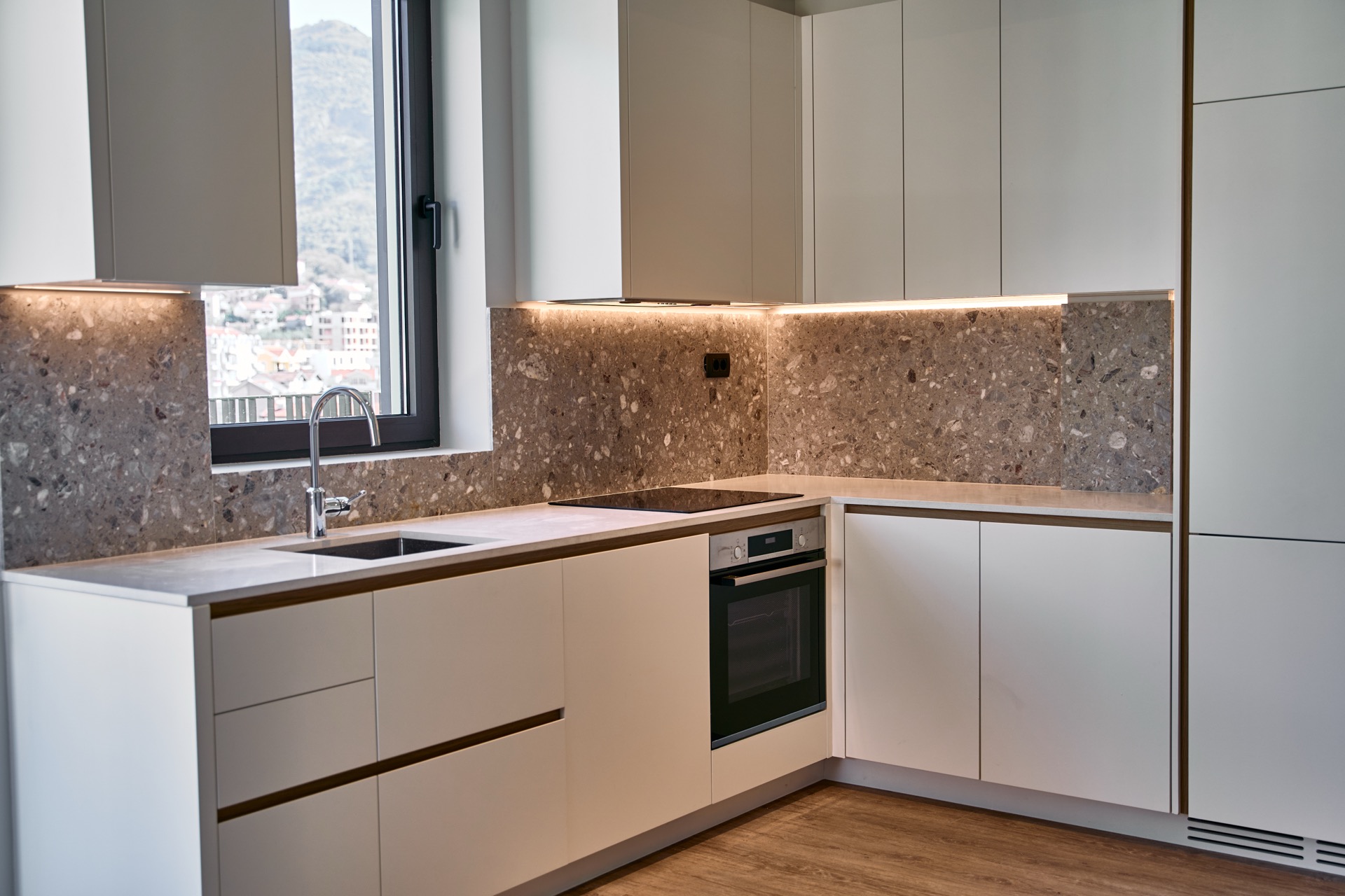 Moderne Küche mit Steinrückwand in der Wohnung Porto Montenegro, Tivat, Montenegro: Einbaugeräte und Bergblick