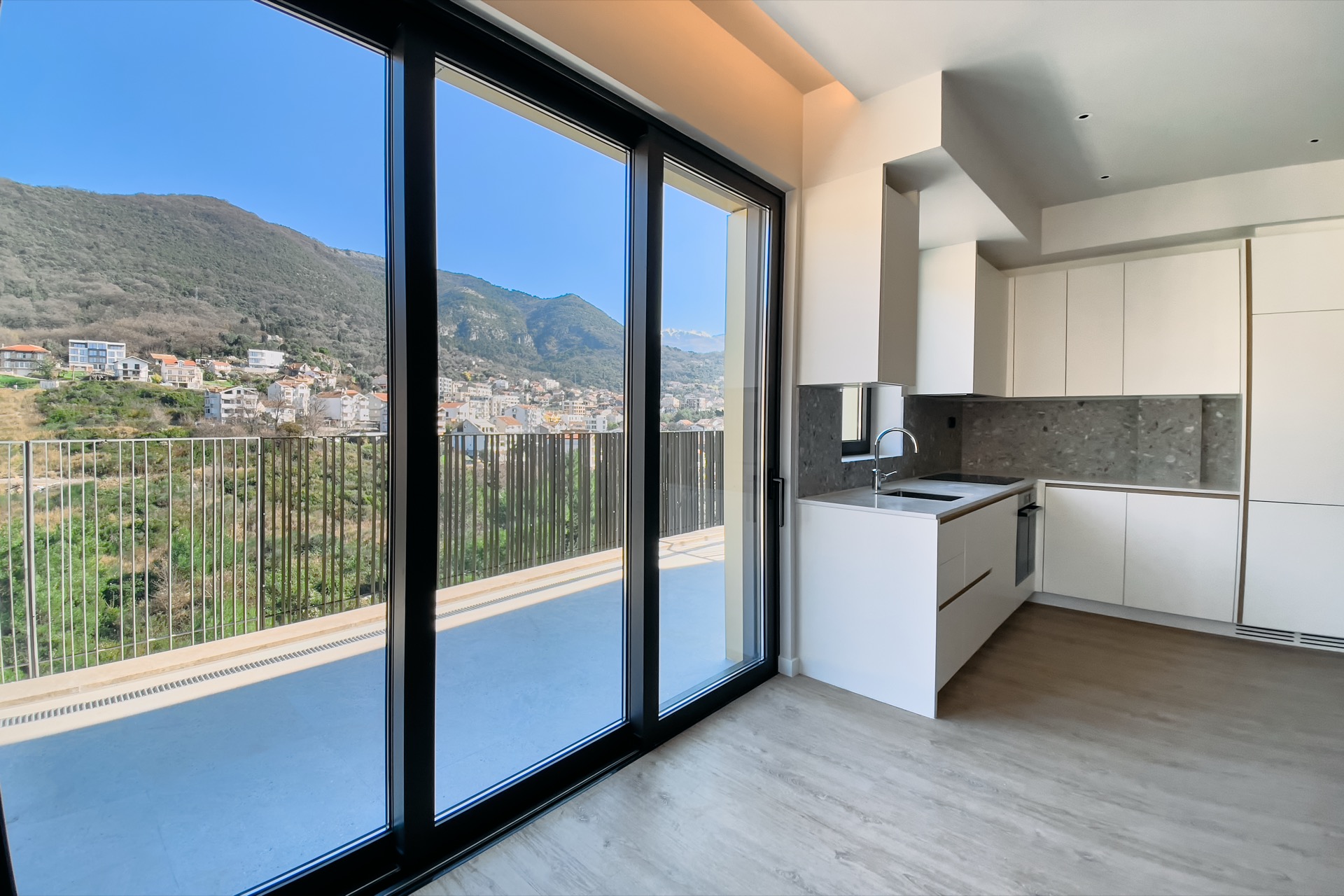 Moderne Küche in einer Wohnung in Tivat, Montenegro, mit Panoramablick auf die Berge und Zugang zu einer großzügigen Terrasse.
