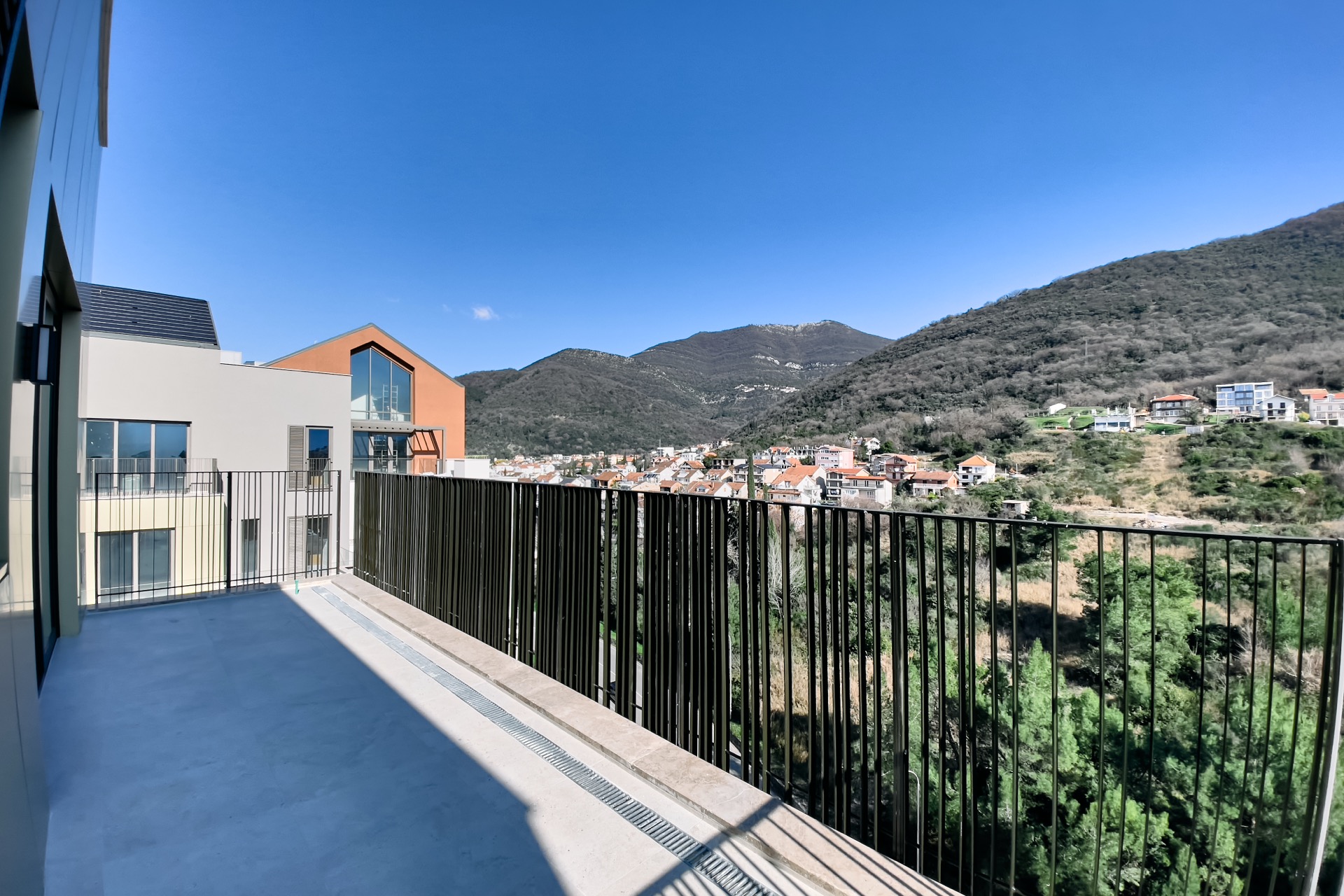 Geräumiger Balkon einer modernen Wohnung in Porto Montenegro, Tivat, Montenegro, mit Panoramablick auf die Berge und die Stadt.
