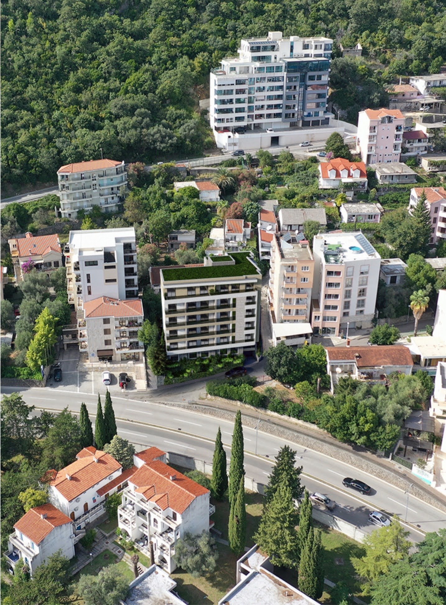 Luftaufnahme eines modernen Wohnkomplexes in Bečići, Montenegro, inmitten grüner Hügel und städtischer Bebauung.