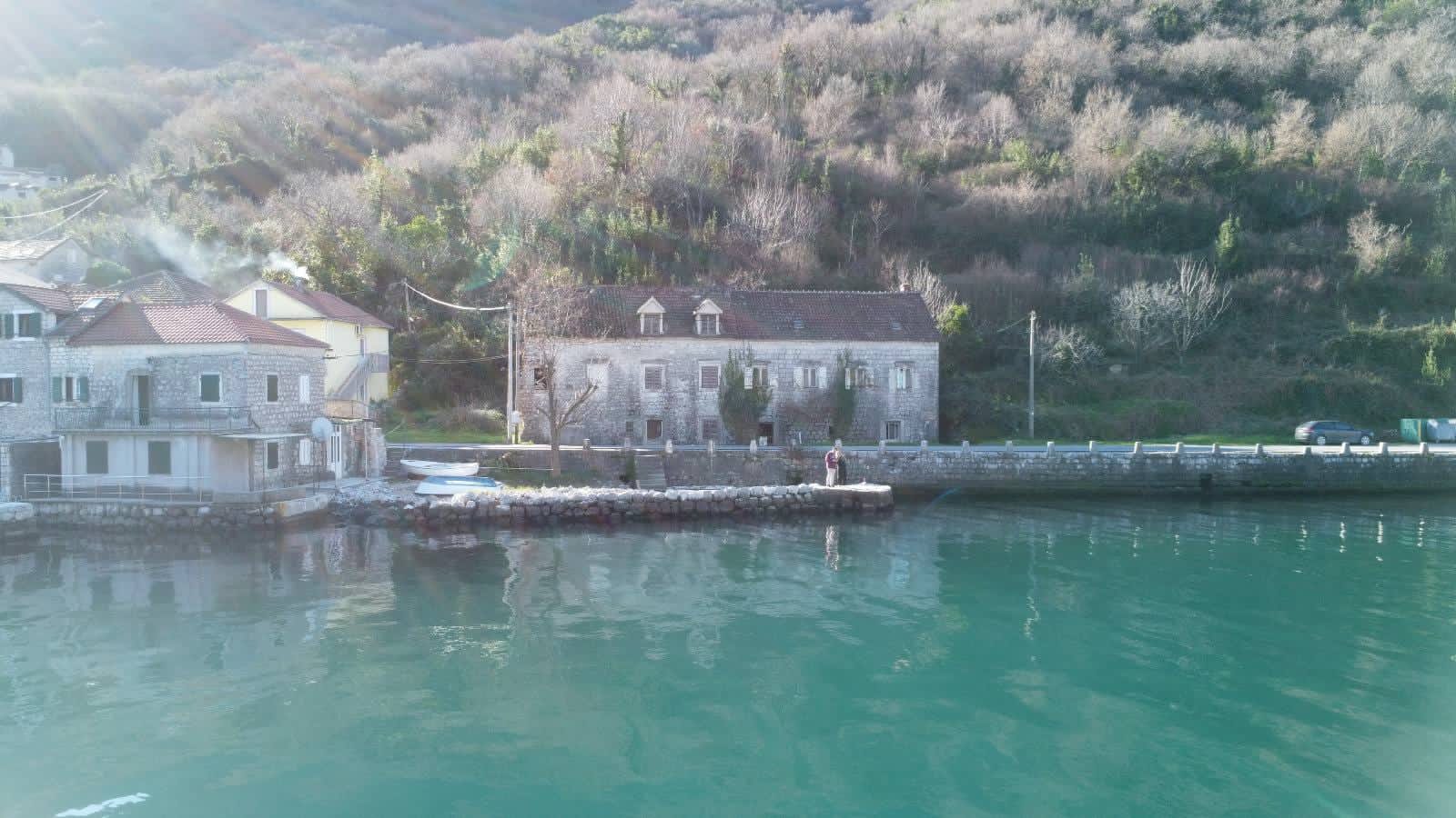 Historisches Steinhaus in erster Meereslinie in Kostanjica, Montenegro: Blick auf die Fassade und den privaten Steg am Wasser.