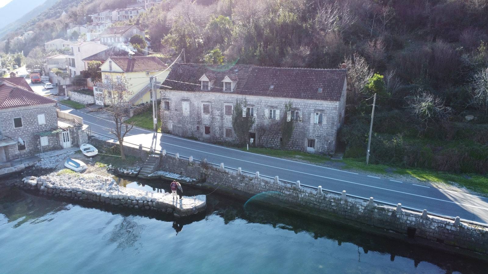 Altes Steinhaus in erster Meereslinie in Kostanica, Montenegro, Luftaufnahme von der Anlegestelle und der Küste.