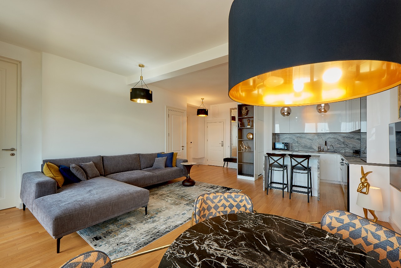 Modernes Wohnzimmer mit grauem Sofa und Küche in einer exklusiven Wohnung in Bečići, Montenegro