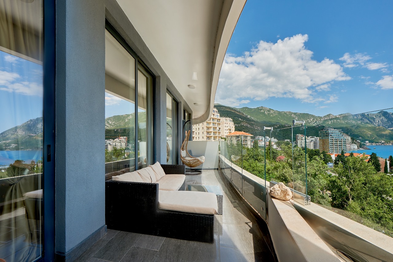 Geräumiger möblierter Balkon der Wohnung in Bečići, Montenegro, mit Panoramablick auf das Meer, die Berge und den Kurort.