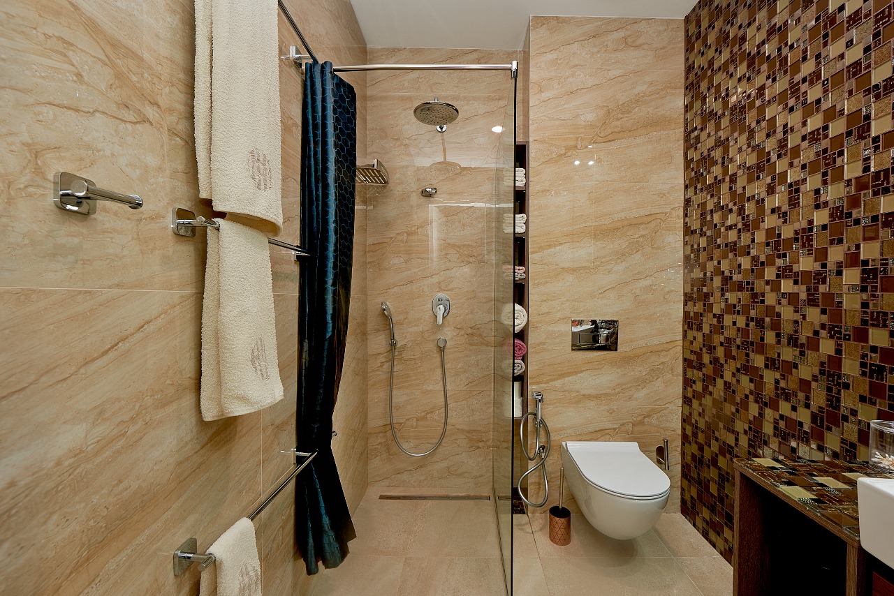Modernes Badezimmer mit Dusche, weißer Toilette und Mosaikfliesen in einer Wohnung in Bečići, Montenegro