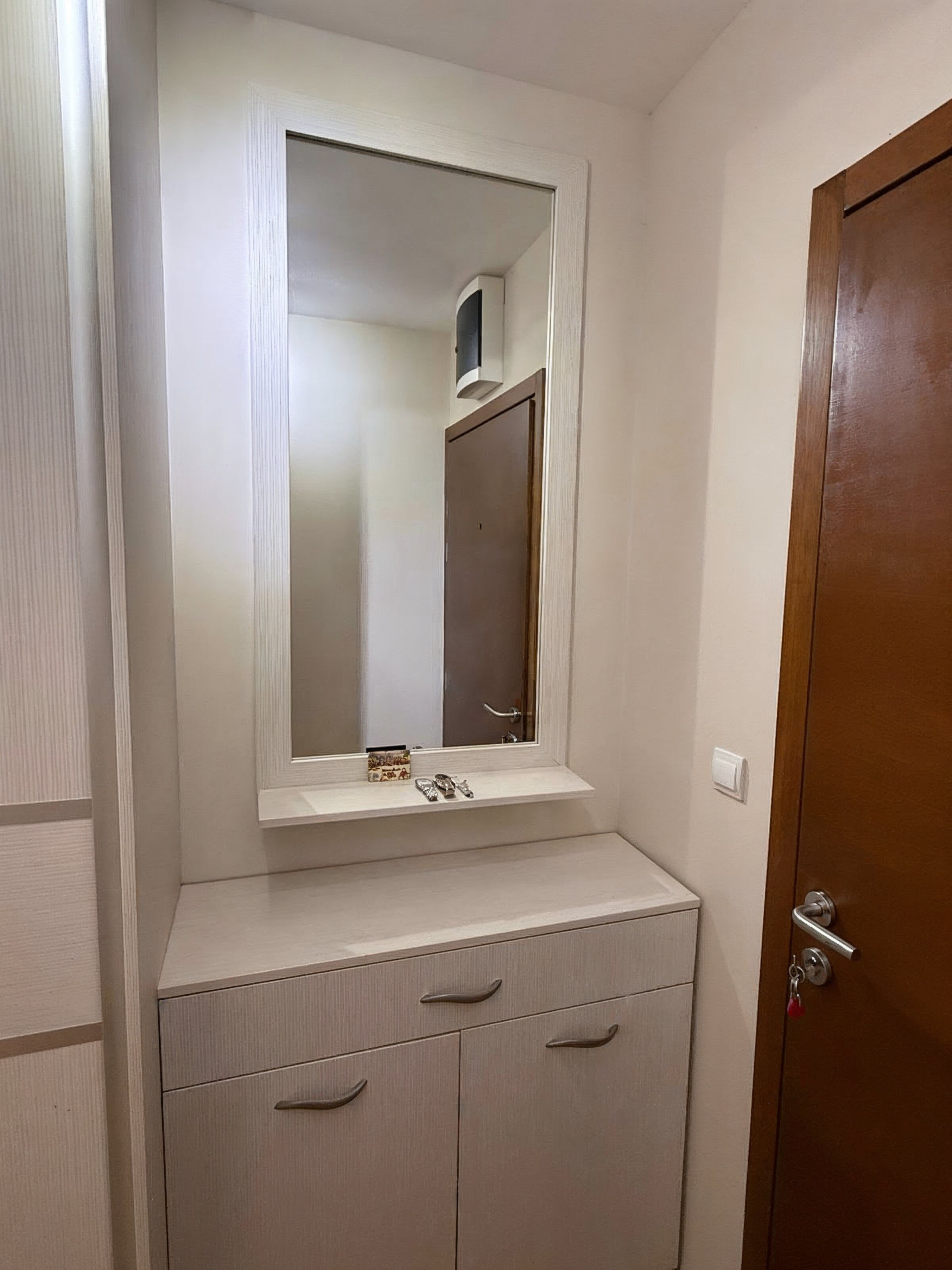 Flur mit weißem Unterschrank und Spiegel in einer modernen Wohnung in Bečići, Montenegro. Innenraum der Unterkunft Nr. 2510.