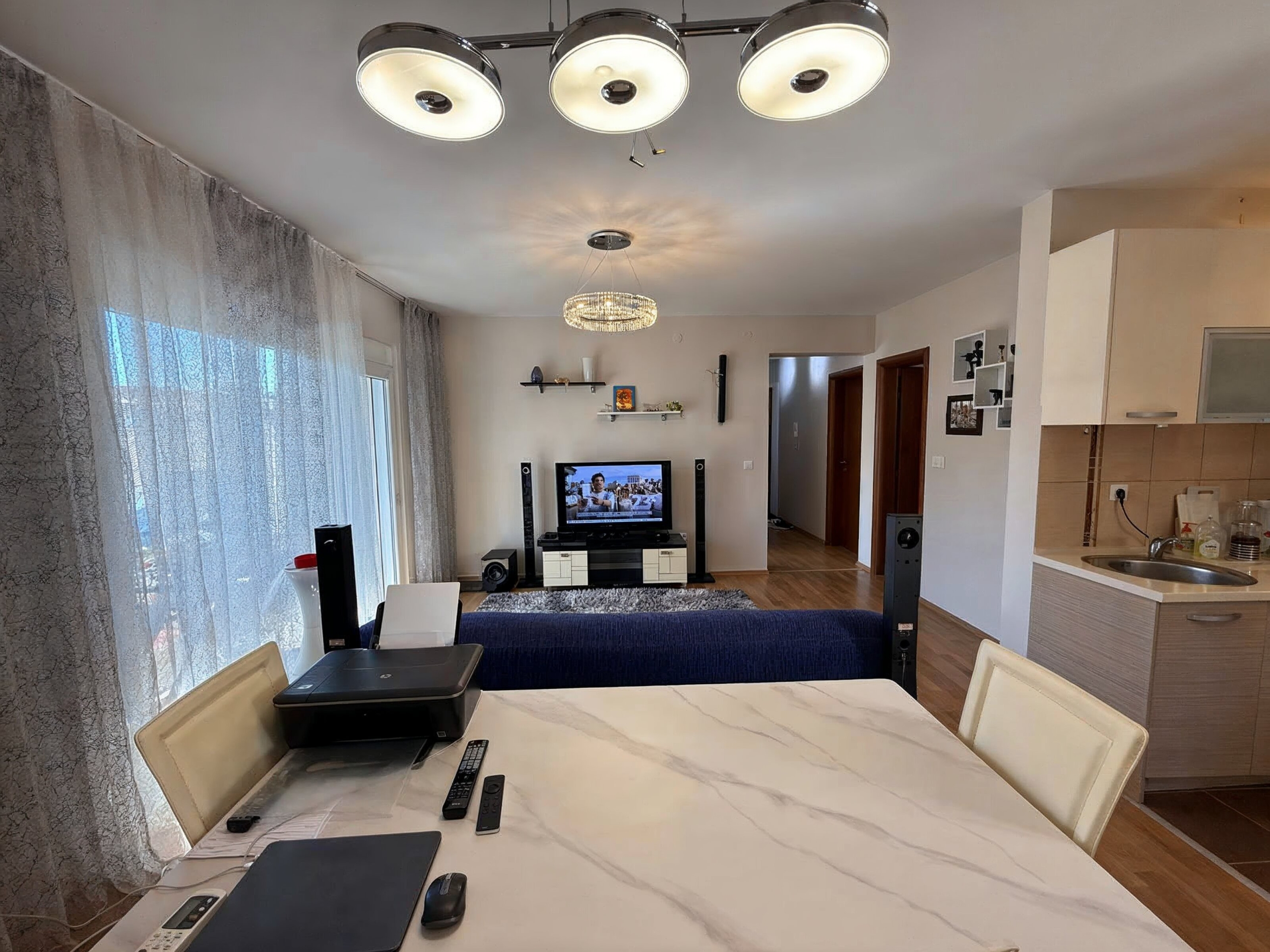 Wohnzimmer mit Essbereich in einer Wohnung, Bečići, Montenegro: helles Interieur, Marmortisch und offene Küche.