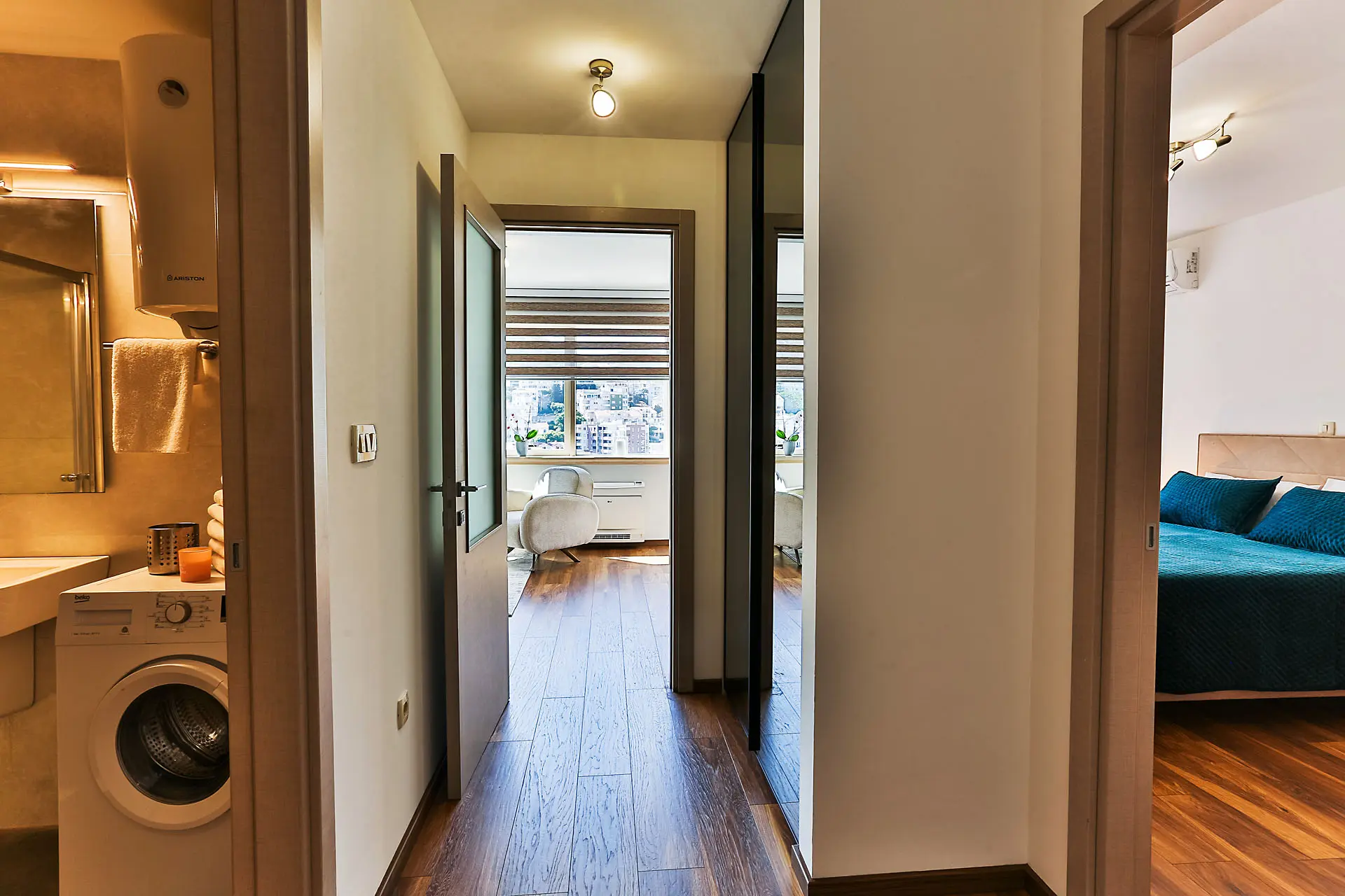 Flur in einer Wohnung in Budva, Montenegro: Blick auf das Schlafzimmer, das Badezimmer mit Waschmaschine und das Wohnzimmer mit Fenster.