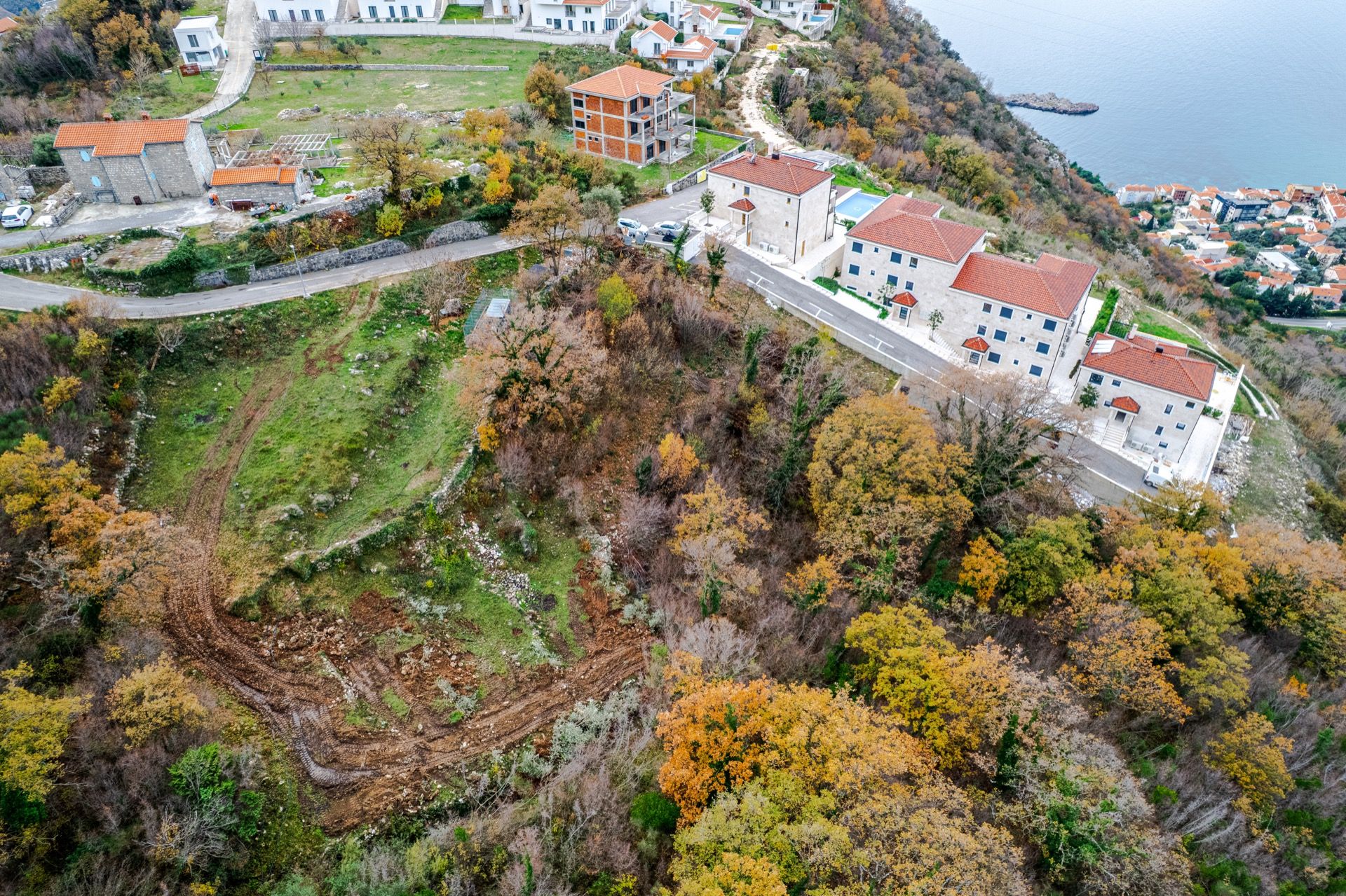 Luftaufnahme einer Wohnanlage in Blizikuće, Montenegro: moderne Häuser mit Ziegeldächern und Meerblick.