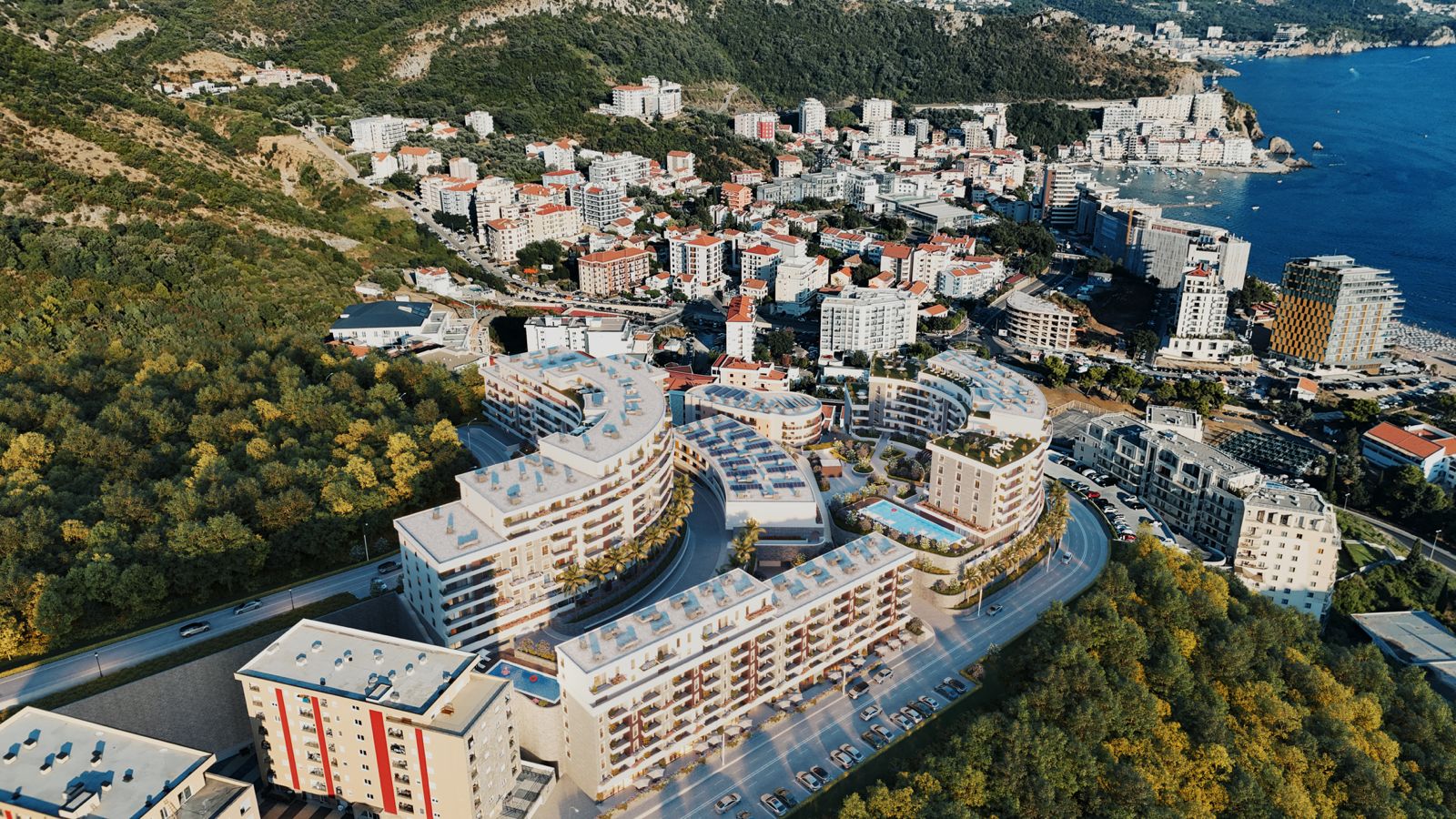 Pogled iz vazduha na stambeni kompleks u Bečićima, Crna Gora: moderne zgrade, bazen i panorama jadranske obale.