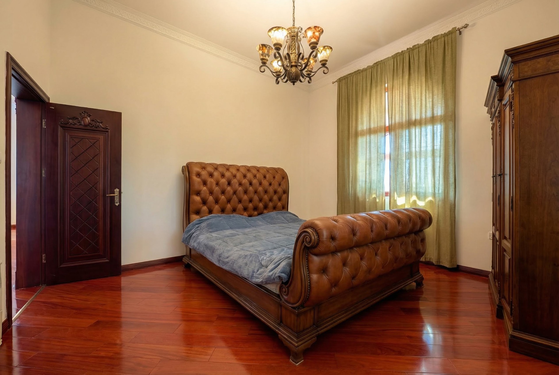Schlafzimmer im klassischen Stil in einer Villa in Luštica, Montenegro: Lederbett, Holzboden und antike Möbel.