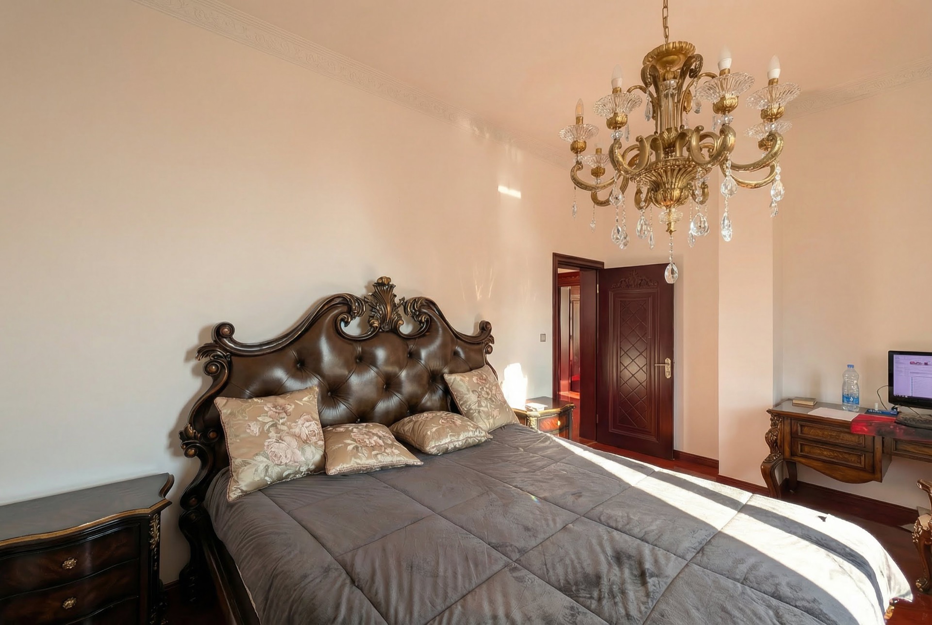 Schlafzimmer im klassischen Stil in einer Villa in Luštica, Montenegro: massives Bett mit Lederkopfteil und Kristalllüster