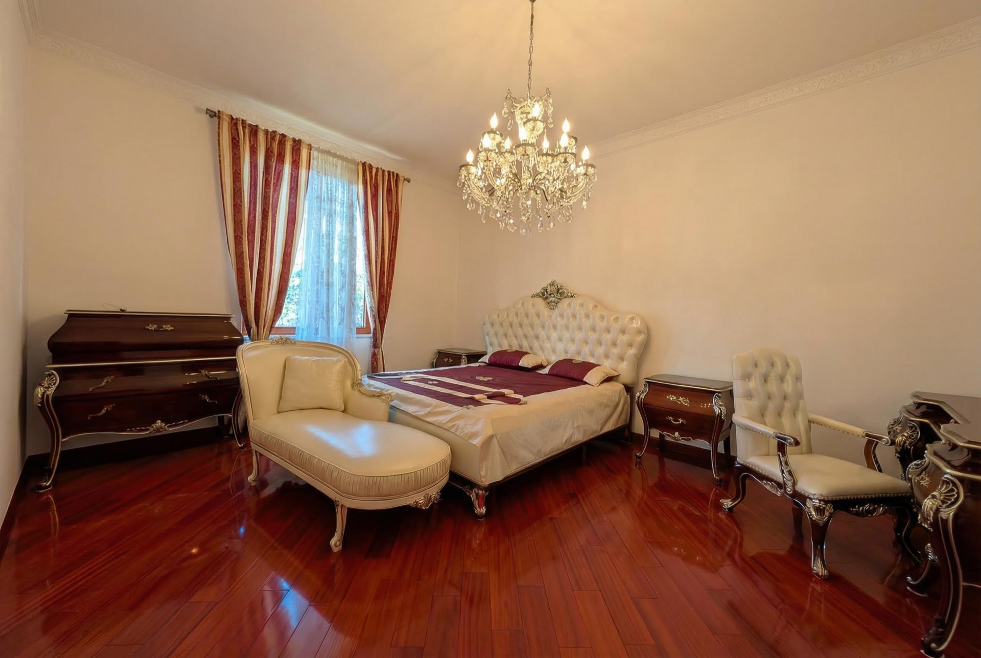 Schlafzimmer im klassischen Stil in einer Villa in Luštica, Montenegro: Doppelbett, Chaiselongue, Kristalllüster und Parkettboden.