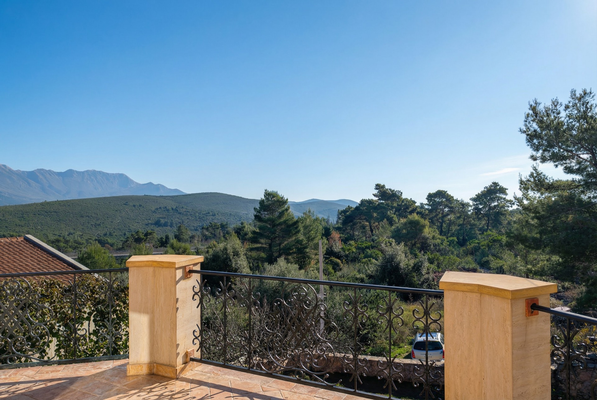 Blick von der Terrasse der Villa in Luštica Bay, Montenegro: schmiedeeisernes Geländer, Panoramablick auf Berge und Nadelwald.