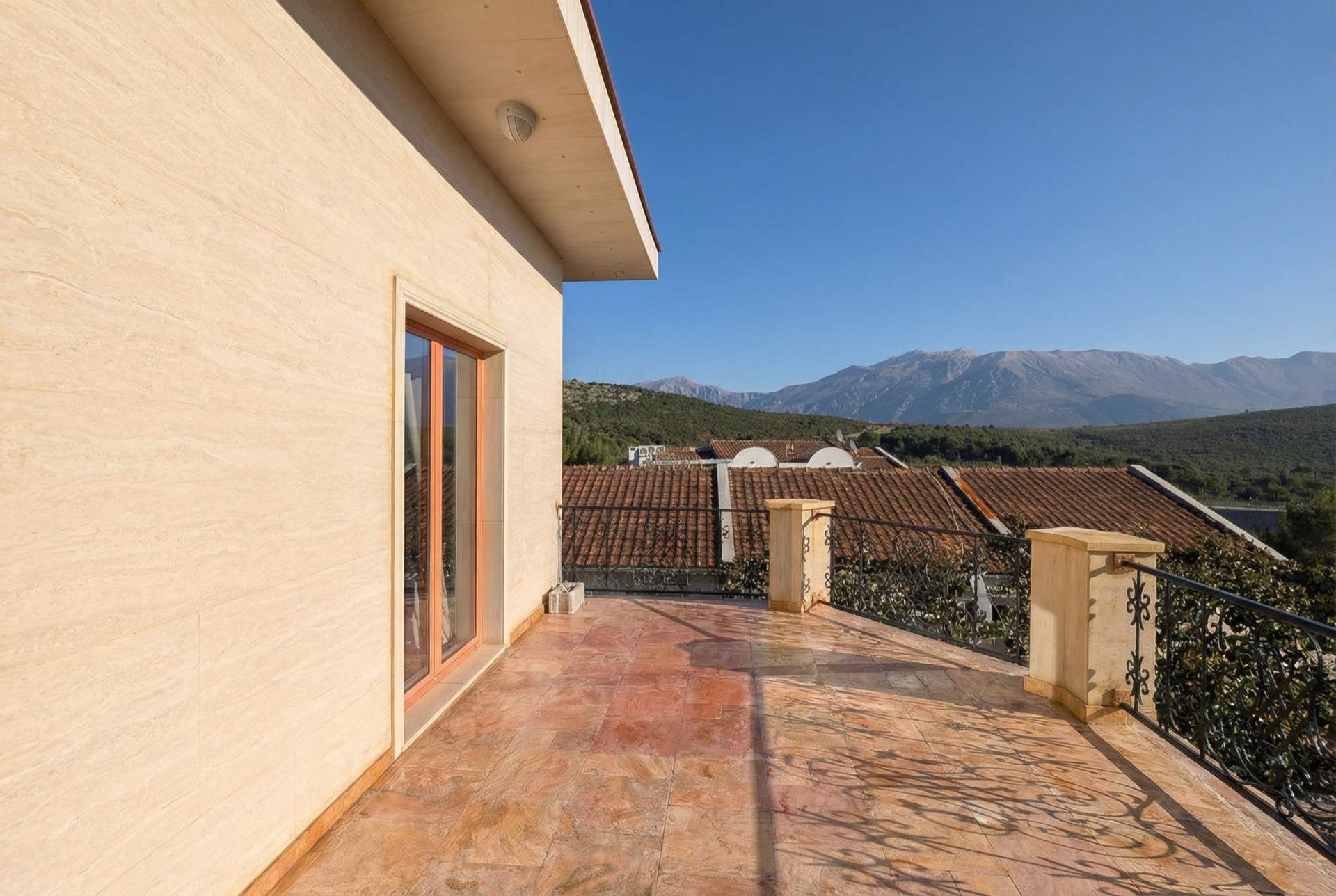 Geräumige Terrasse der Villa in Luštica Bay, Montenegro, mit Steinverkleidung, schmiedeeisernem Geländer und Bergblick.
