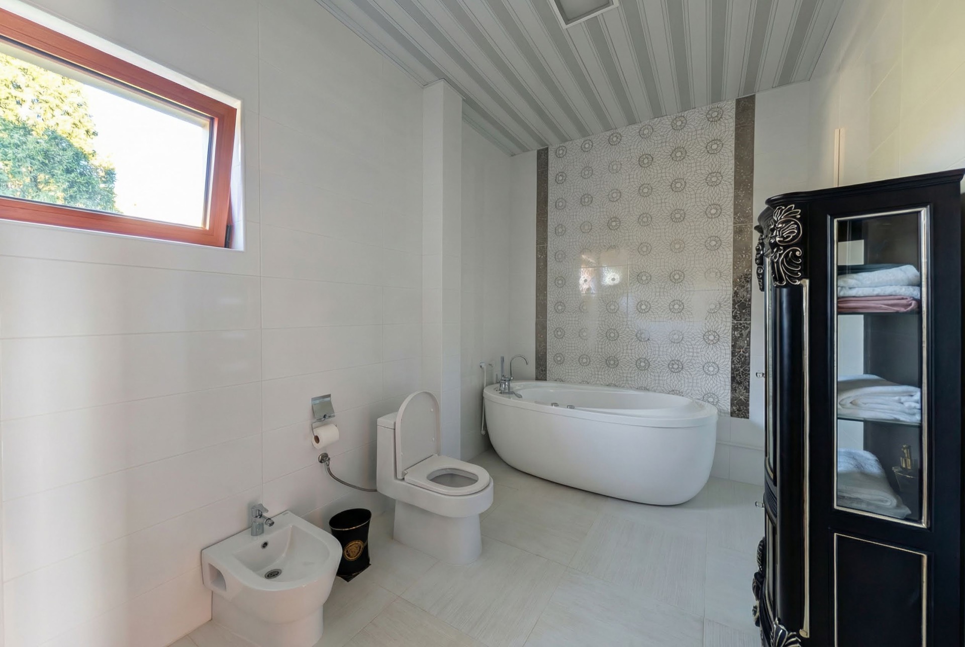 Badezimmer in einer Villa in Luštica, Montenegro: freistehende Badewanne, Bidet, Toilette und schwarzer Vitrinenschrank.