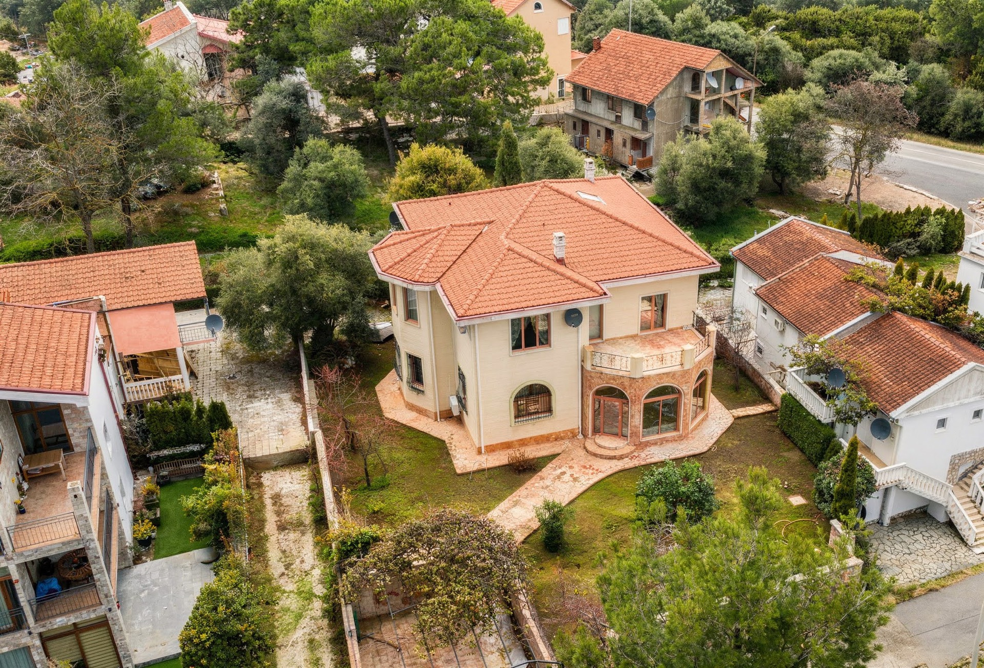 Blick von oben auf eine zweistöckige Villa mit Ziegeldach und Garten in Luštica, Montenegro: Außenansicht des Hauses mit Terrasse.
