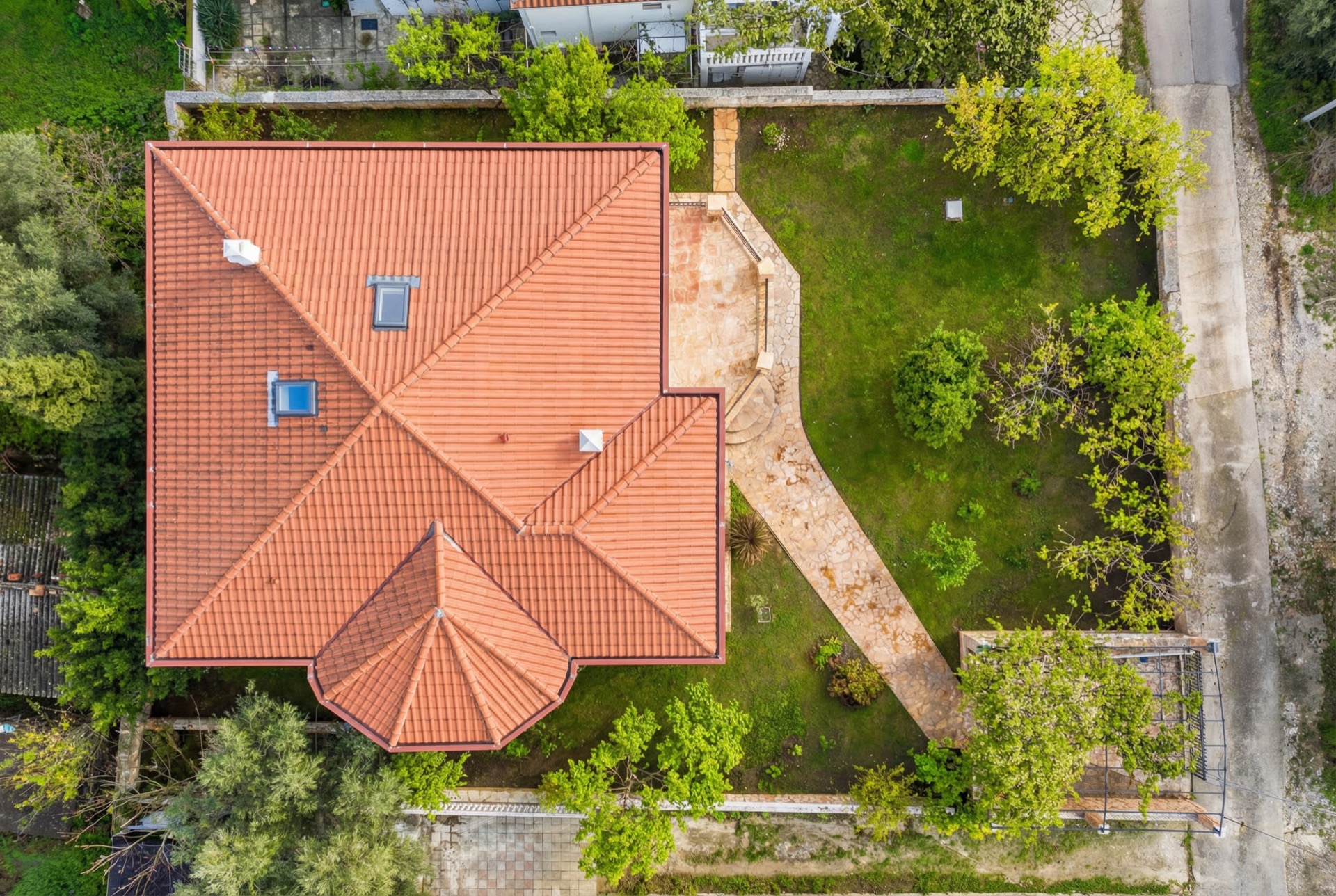 Blick von oben auf eine Villa mit Ziegeldach, Terrasse und grünem Garten in Luštica, Montenegro.