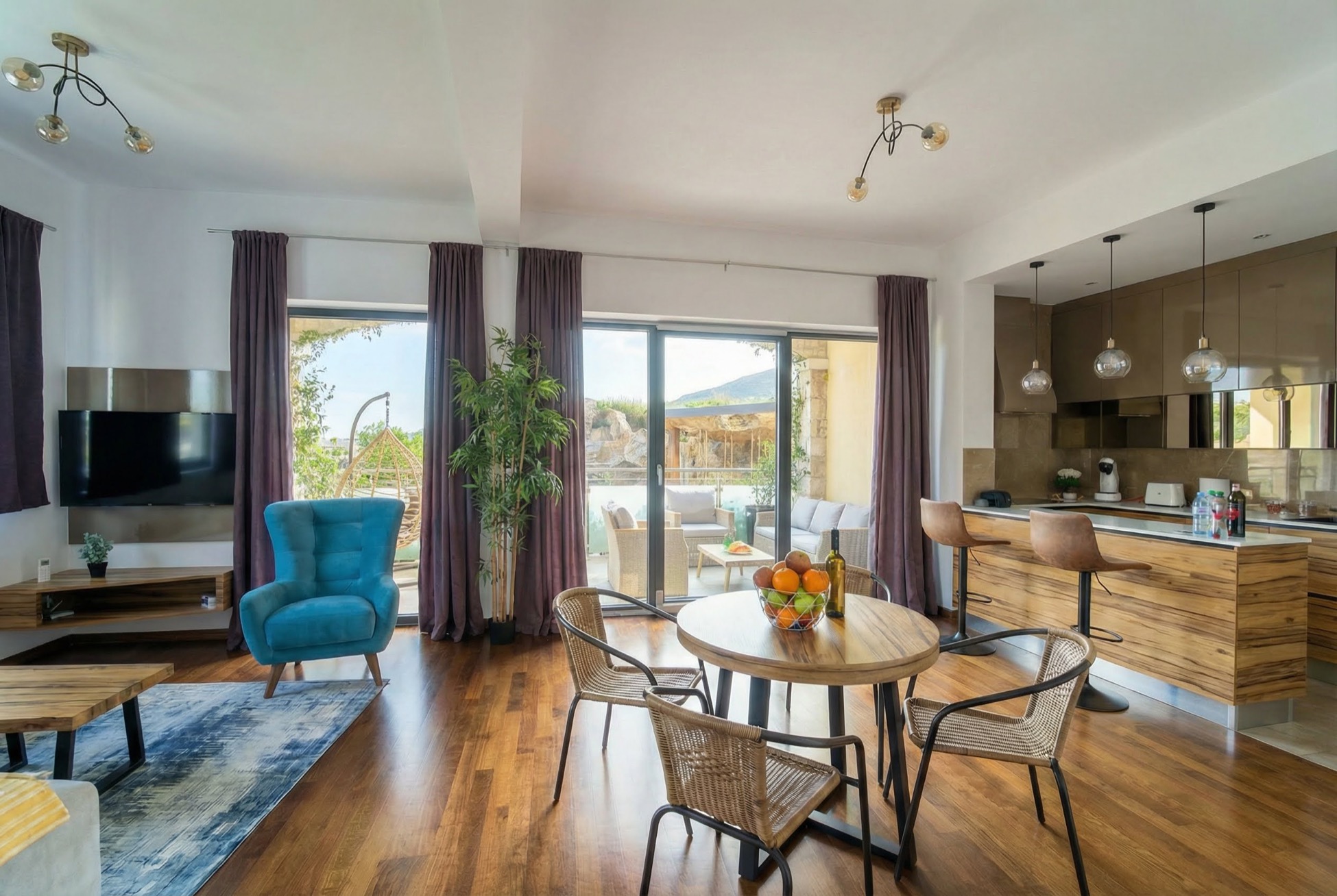 Modernes Wohnzimmer mit Küche in einem Apartment in Bečići, Montenegro: Essbereich, blauer Sessel und Zugang zur Terrasse.
