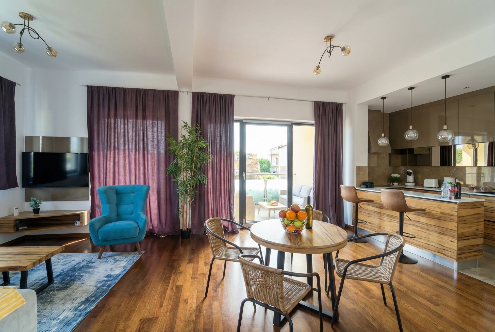 Modernes Wohnzimmer mit Küche in einem Apartment in Bečići, Montenegro: blauer Sessel, Essbereich und Zugang zur Terrasse.