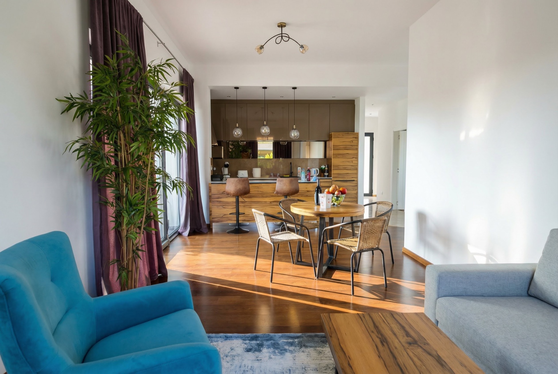 Modernes Wohnzimmer mit Küche in einem Apartment, Bečići, Montenegro: blauer Sessel, Essbereich und stilvolles Interieur.