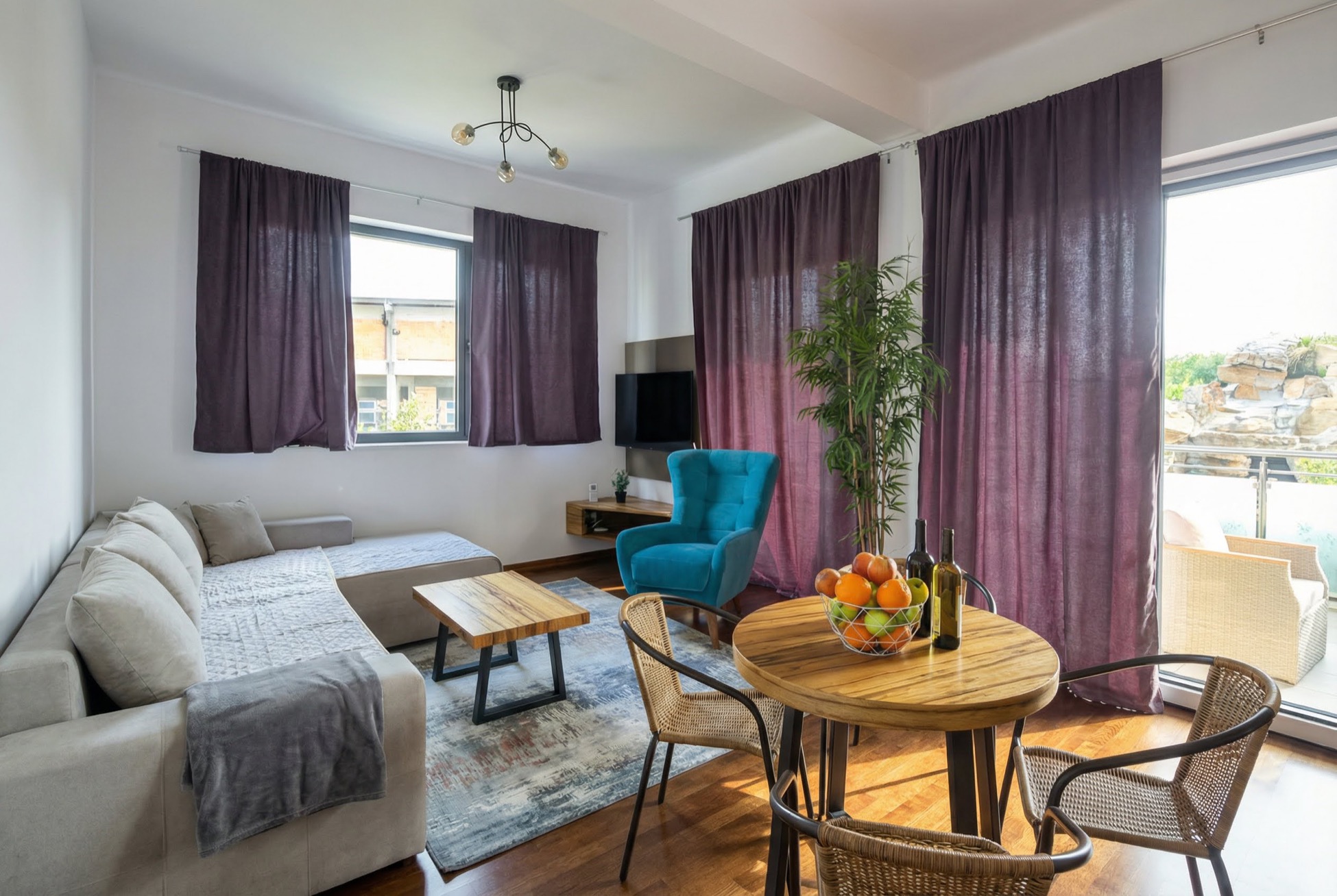 Modernes Wohnzimmer in einem Apartment in Bečići, Montenegro: helles Sofa, blauer Sessel, Essbereich und Zugang zur Terrasse.