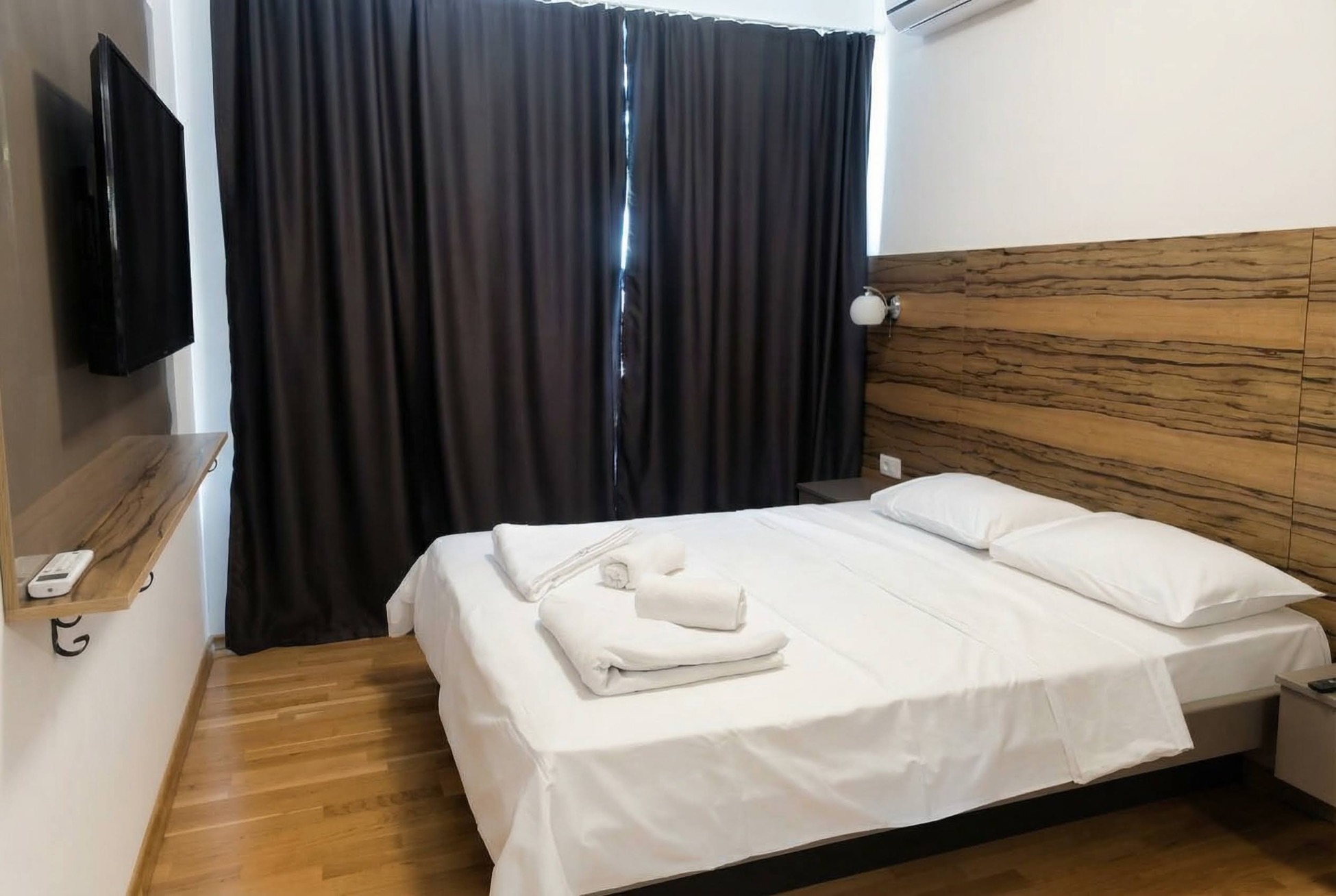 Schlafzimmer in einem Apartment in Bečići, Montenegro: Doppelbett, holzverkleidete Wand, TV und Parkettboden.