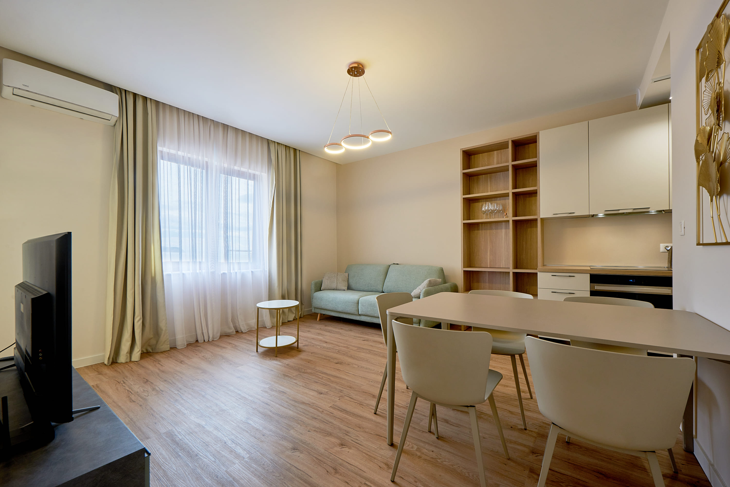 Salon moderne avec cuisine dans un appartement, Bečići, Monténégro : meubles clairs, canapé et coin repas.