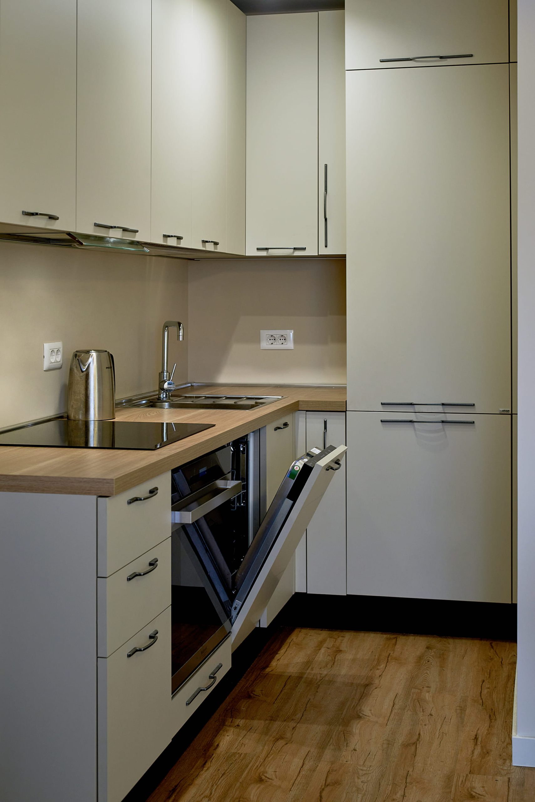 Cuisine moderne et lumineuse dans un appartement à Bečići, Monténégro : électroménager intégré, lave-vaisselle et plan de travail en bois.