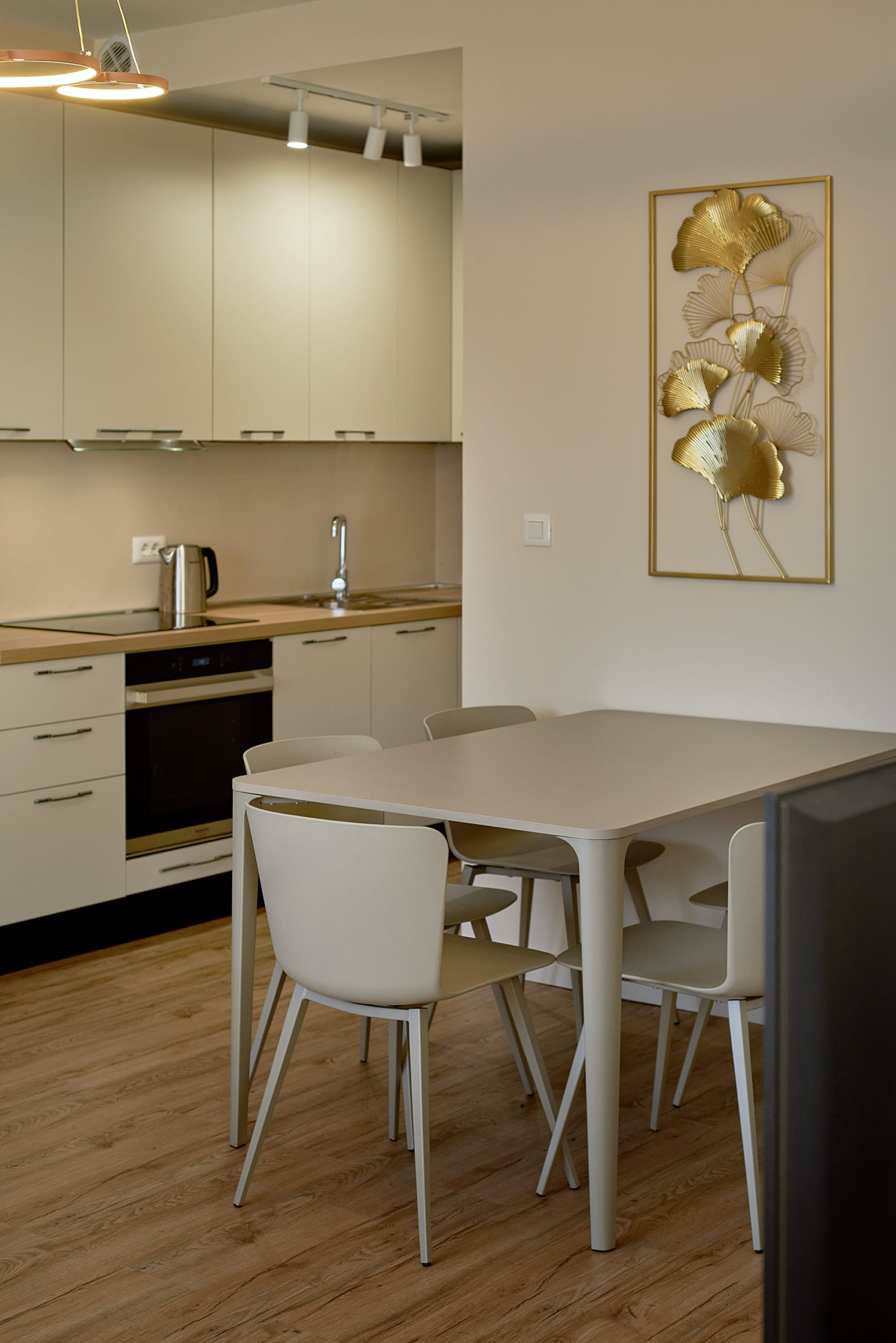 Cuisine-salle à manger moderne dans un appartement à Bečići, Monténégro : meubles de cuisine clairs, coin repas et décoration murale.