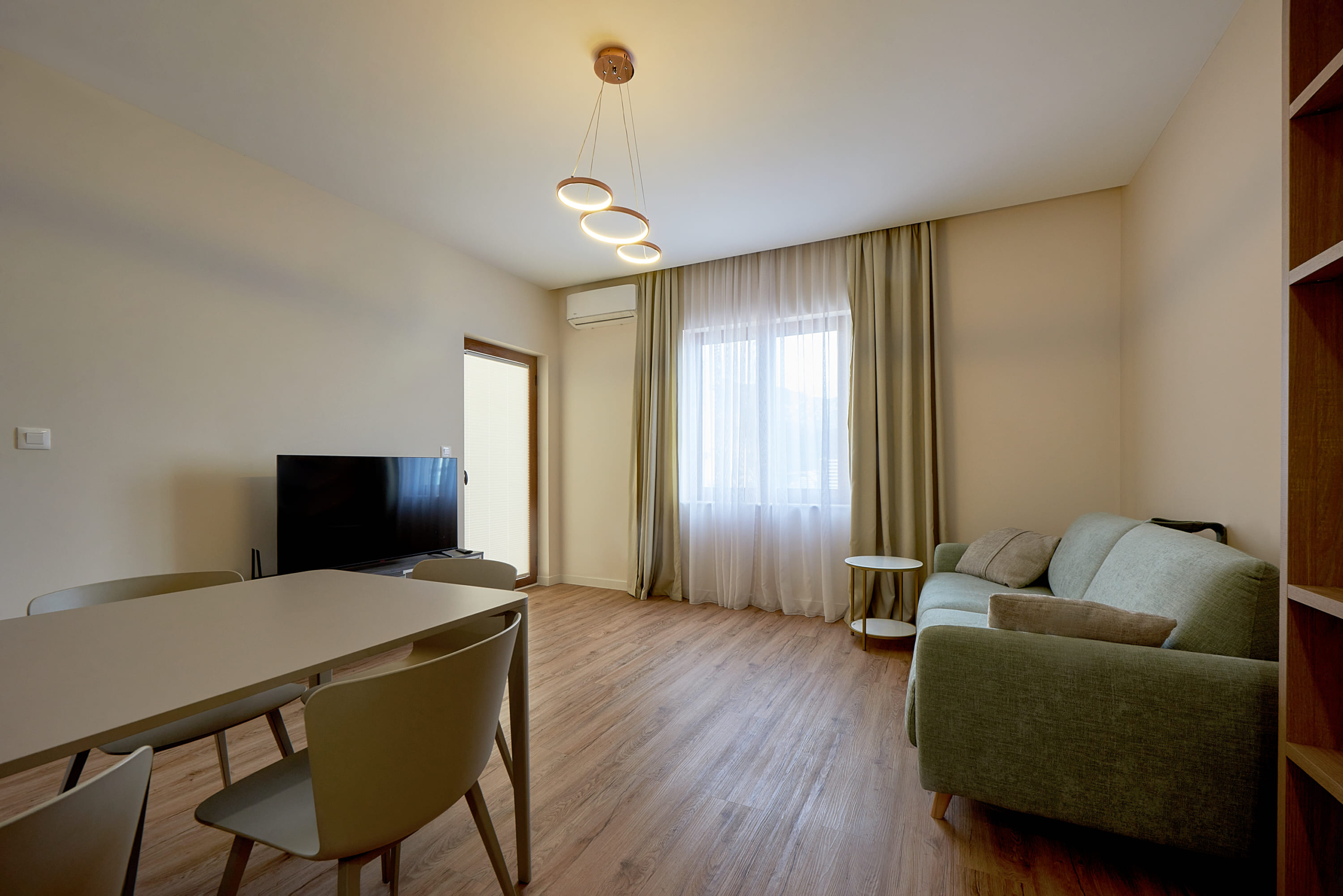 Salon moderne avec coin repas et canapé dans un appartement à Bečići, Monténégro. Intérieur lumineux avec espace télévision.