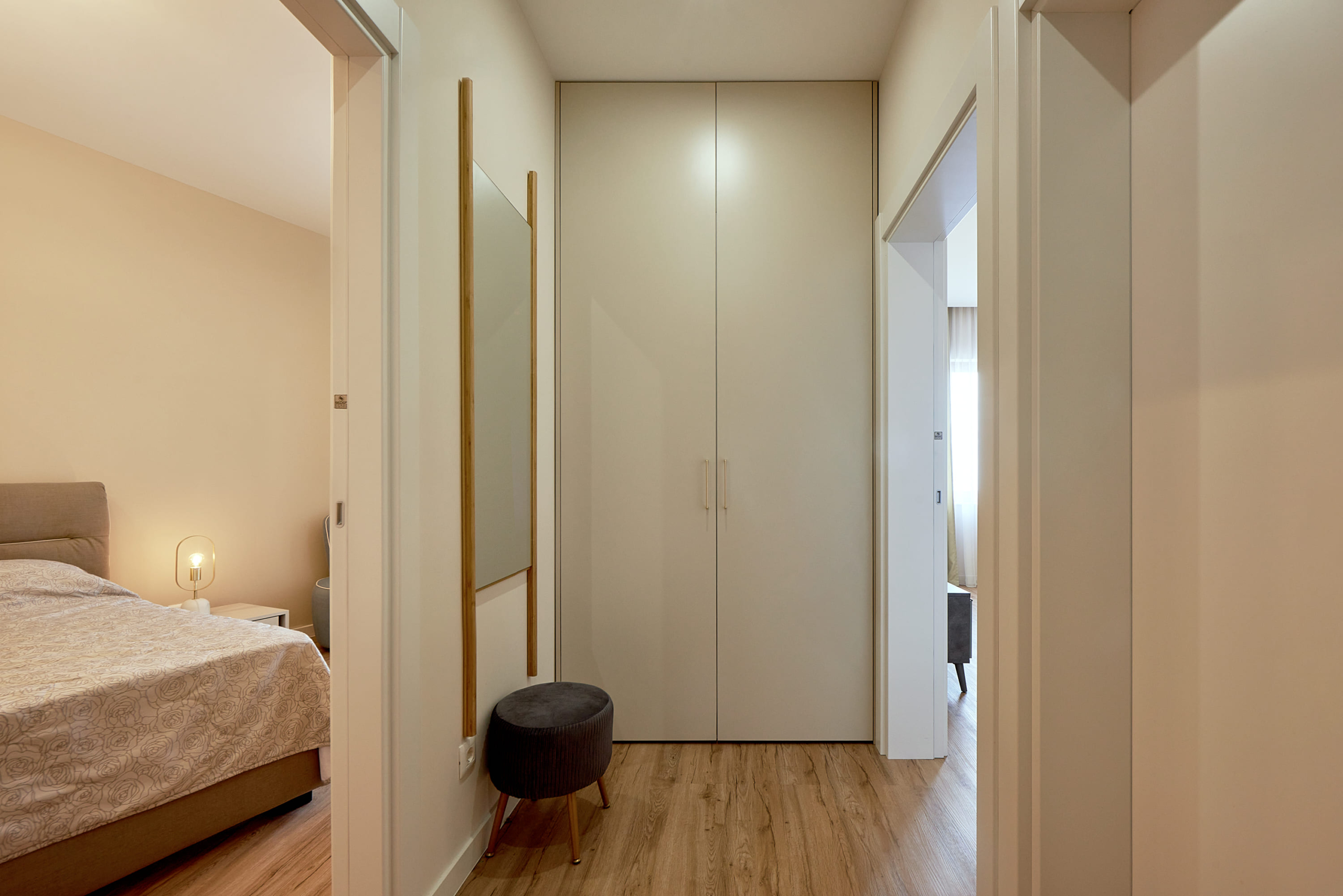 Couloir lumineux avec placard intégré et miroir dans un appartement à Bečići, Monténégro. Vue sur une chambre cosy.
