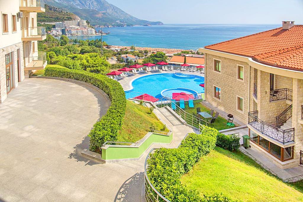 Vue sur la piscine et la mer depuis les appartements à Bečići, Monténégro : complexe résidentiel moderne avec terrasse et espace de détente.