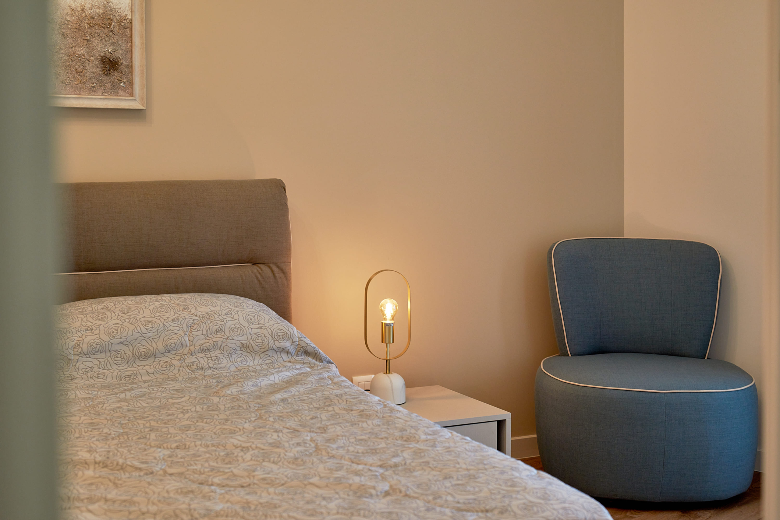 Chambre cosy dans un appartement, Bečići, Monténégro : lit double, fauteuil bleu et lampe design.